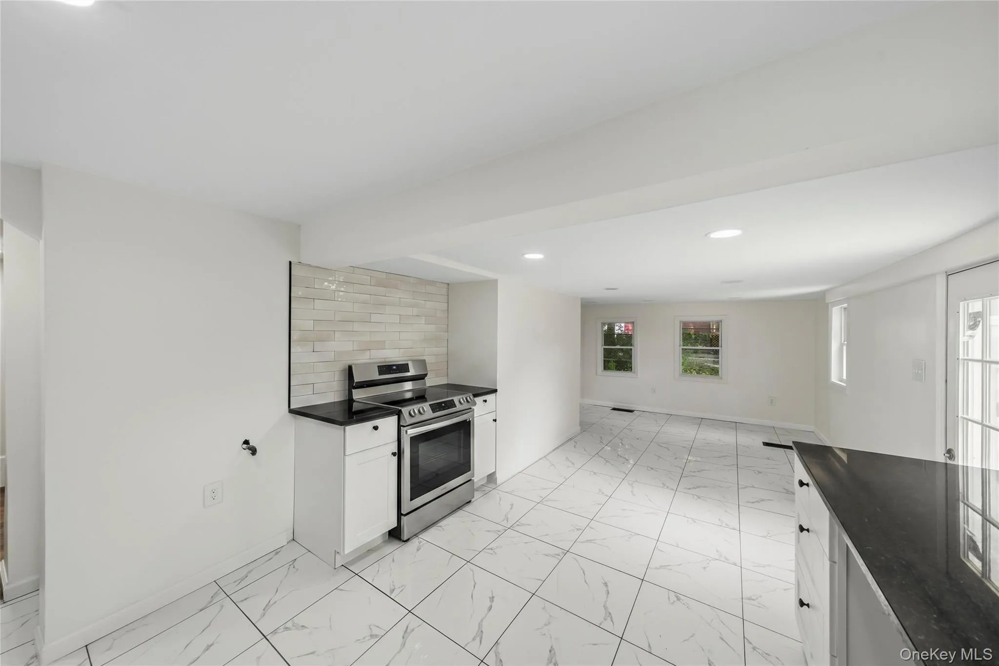 Spacious kitchen featuring stainless steel appliances, white cabinetry with hardware accents, tile flooring throughout, and recessed ceiling lighting Spacious kitchen featuring stainless steel appliances, white cabinetry with hardware accents, tile flooring throughout, and recessed ceiling lighting