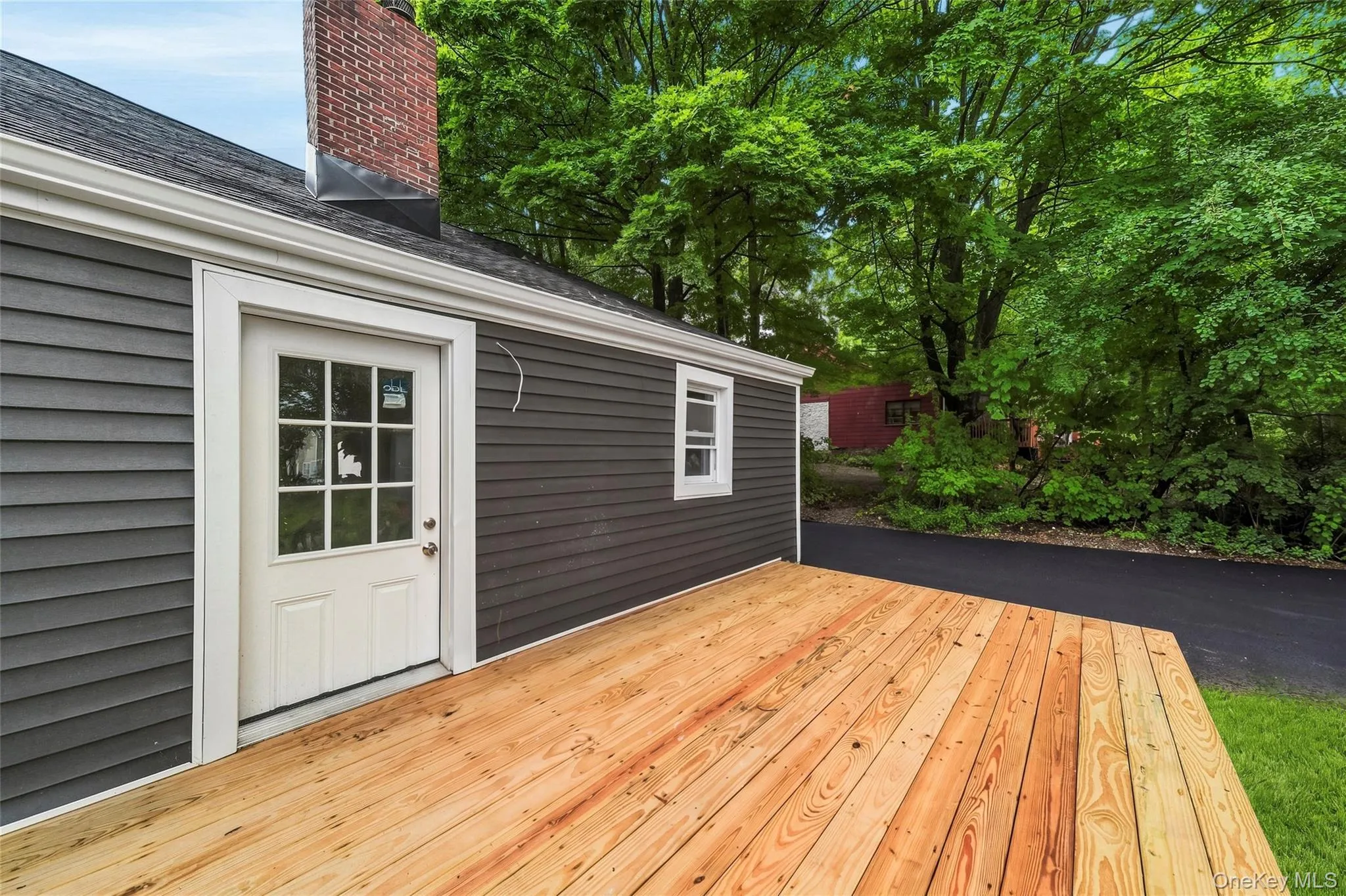 Expansive wood deck with a white paneled door, offering direct outdoor access Expansive wood deck with a white paneled door, offering direct outdoor access