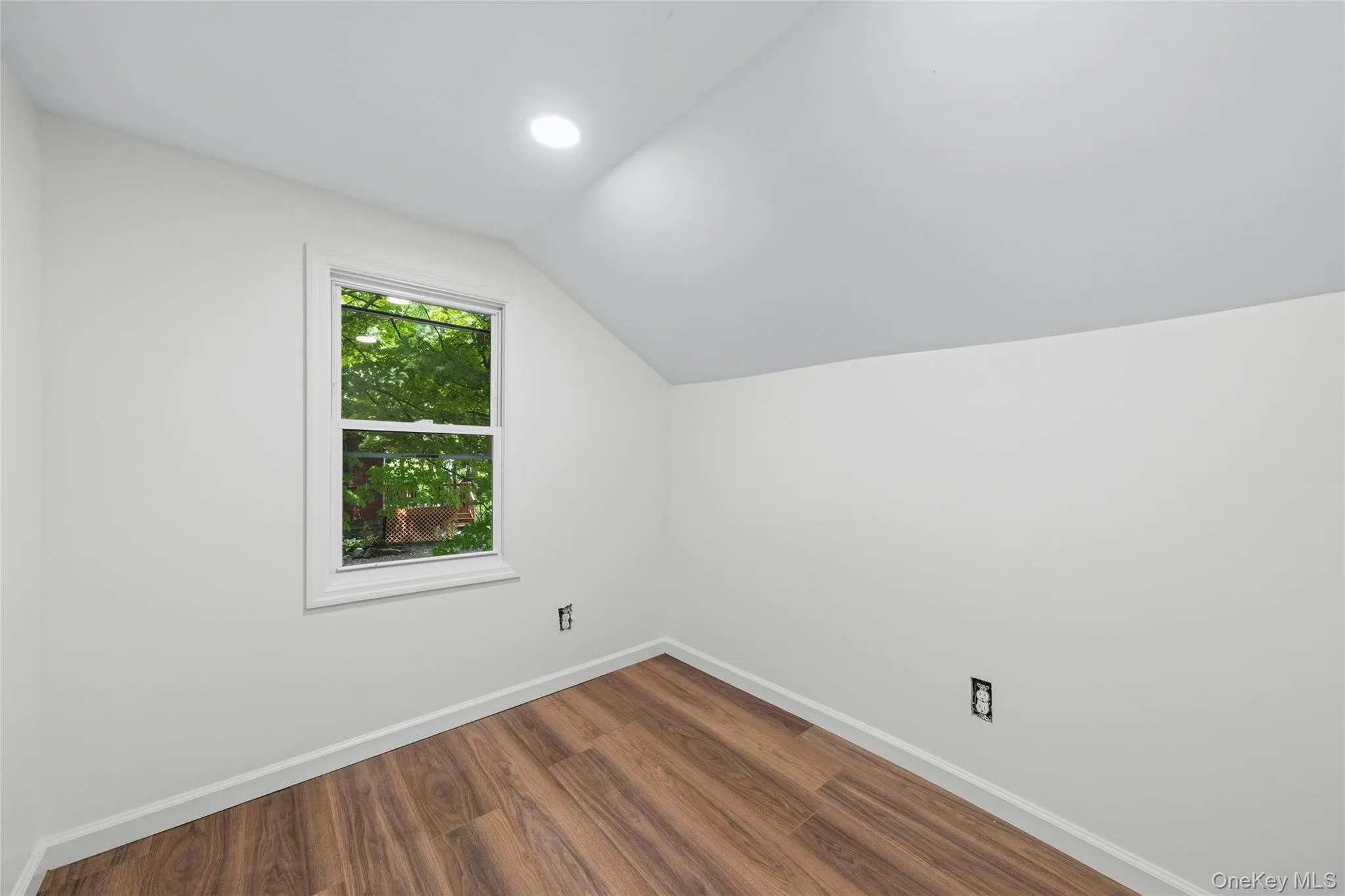 Bright and airy bedroom featuring soaring vaulted ceilings, recessed lighting, and wood-finish flooring throughout Bright and airy bedroom featuring soaring vaulted ceilings, recessed lighting, and wood-finish flooring throughout