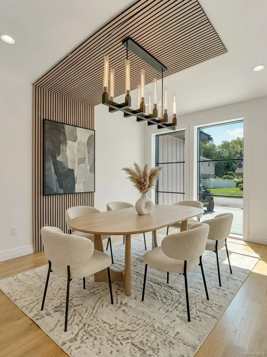 Dining space featuring wood-finish flooring, a contemporary chandelier, two large windows, and a slatted wood accent wall and ceiling panel Dining space featuring wood-finish flooring, a contemporary chandelier, two large windows, and a slatted wood accent wall and ceiling panel