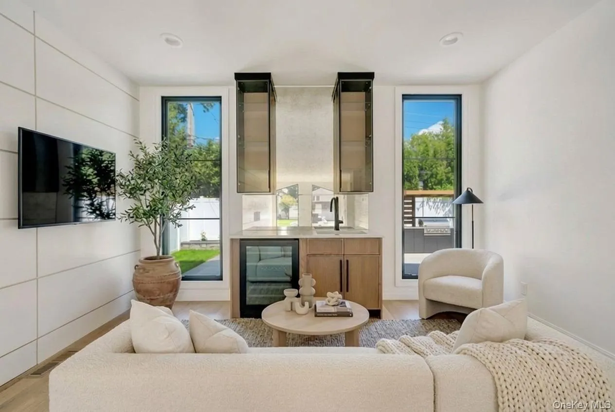 Integrated wet bar featuring a beverage cooler, sink with a matte black faucet, and upper glass-front cabinetry Integrated wet bar featuring a beverage cooler, sink with a matte black faucet, and upper glass-front cabinetry