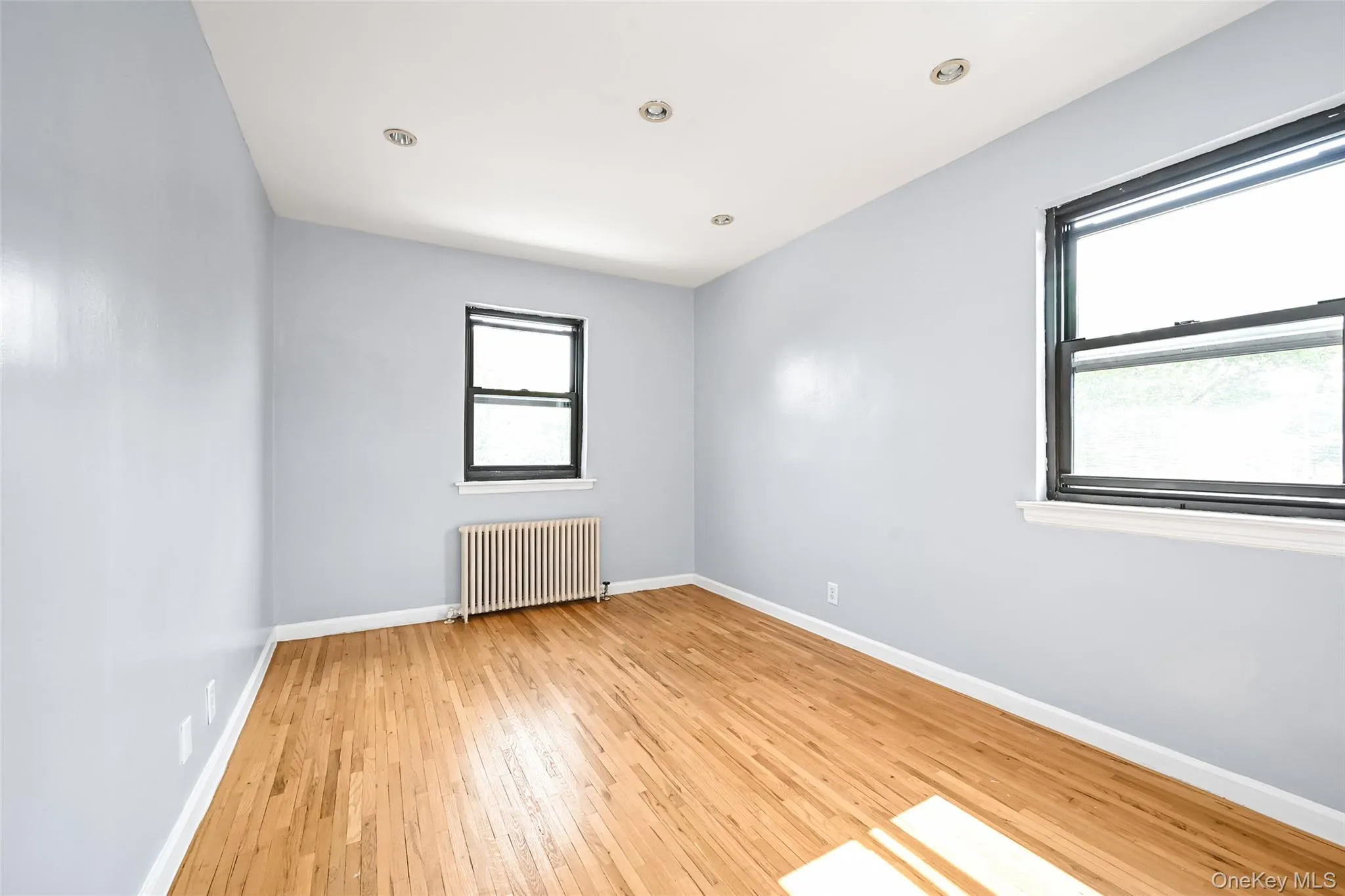 Hardwood flooring throughout, featuring light blue walls and multiple windows Hardwood flooring throughout, featuring light blue walls and multiple windows
