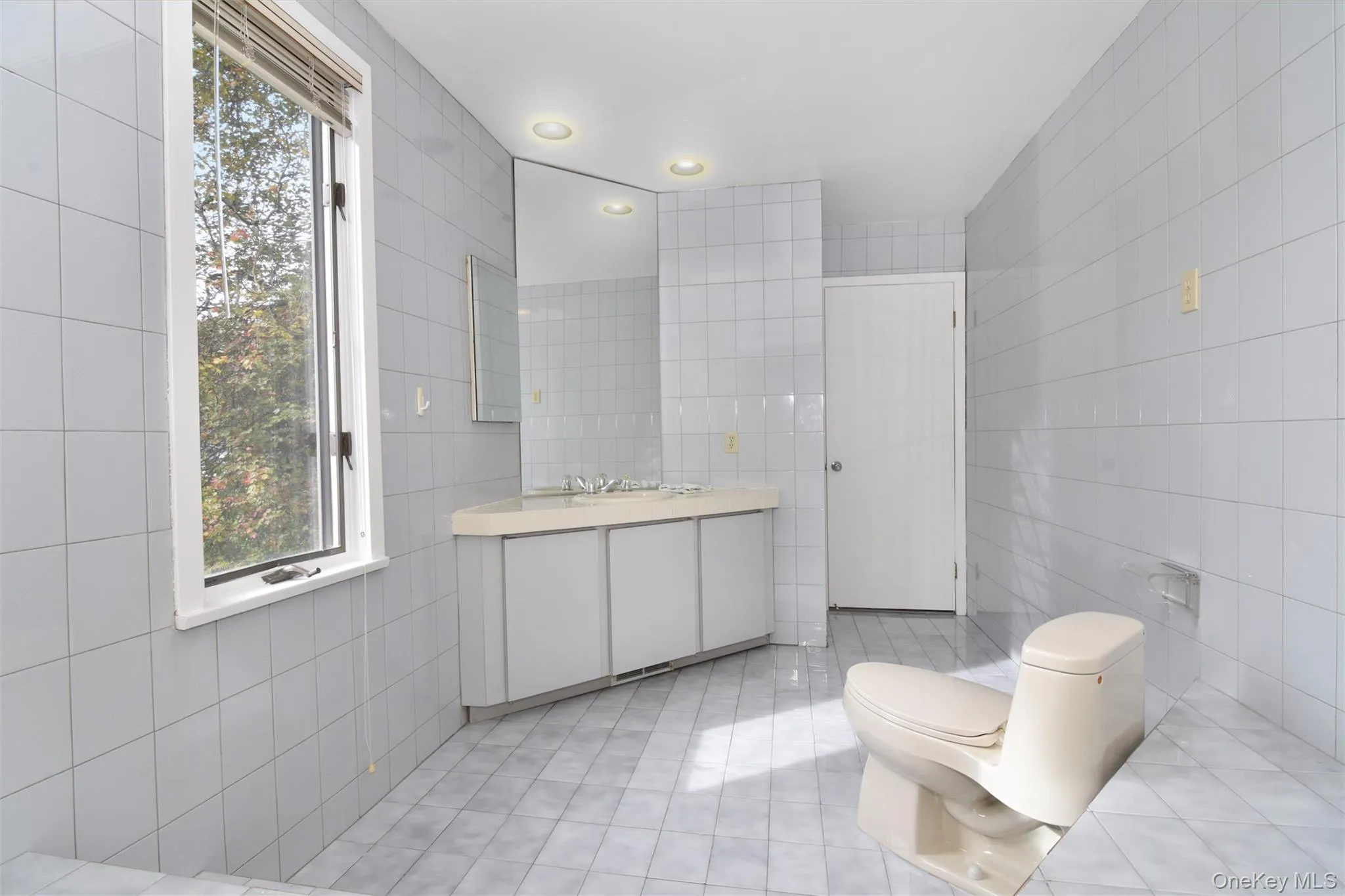 Primary full bath featuring tile walls, light tile patterned floors, recessed lighting, and vanity Primary full bath featuring tile walls, light tile patterned floors, recessed lighting, and vanity