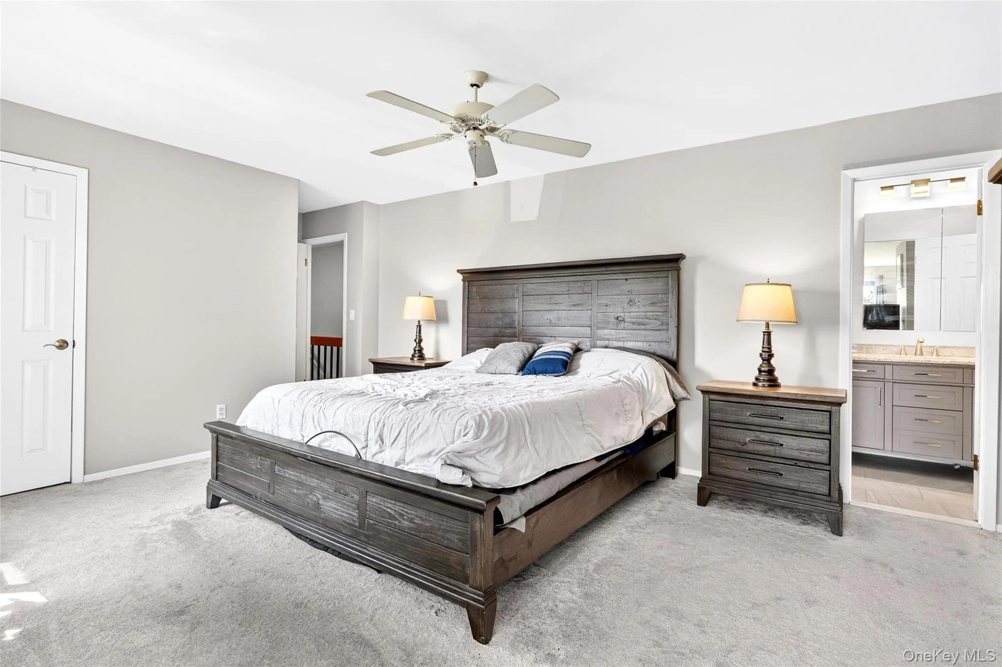 Spacious bedroom featuring light grey carpeting, painted walls, and a ceiling fan Spacious bedroom featuring light grey carpeting, painted walls, and a ceiling fan