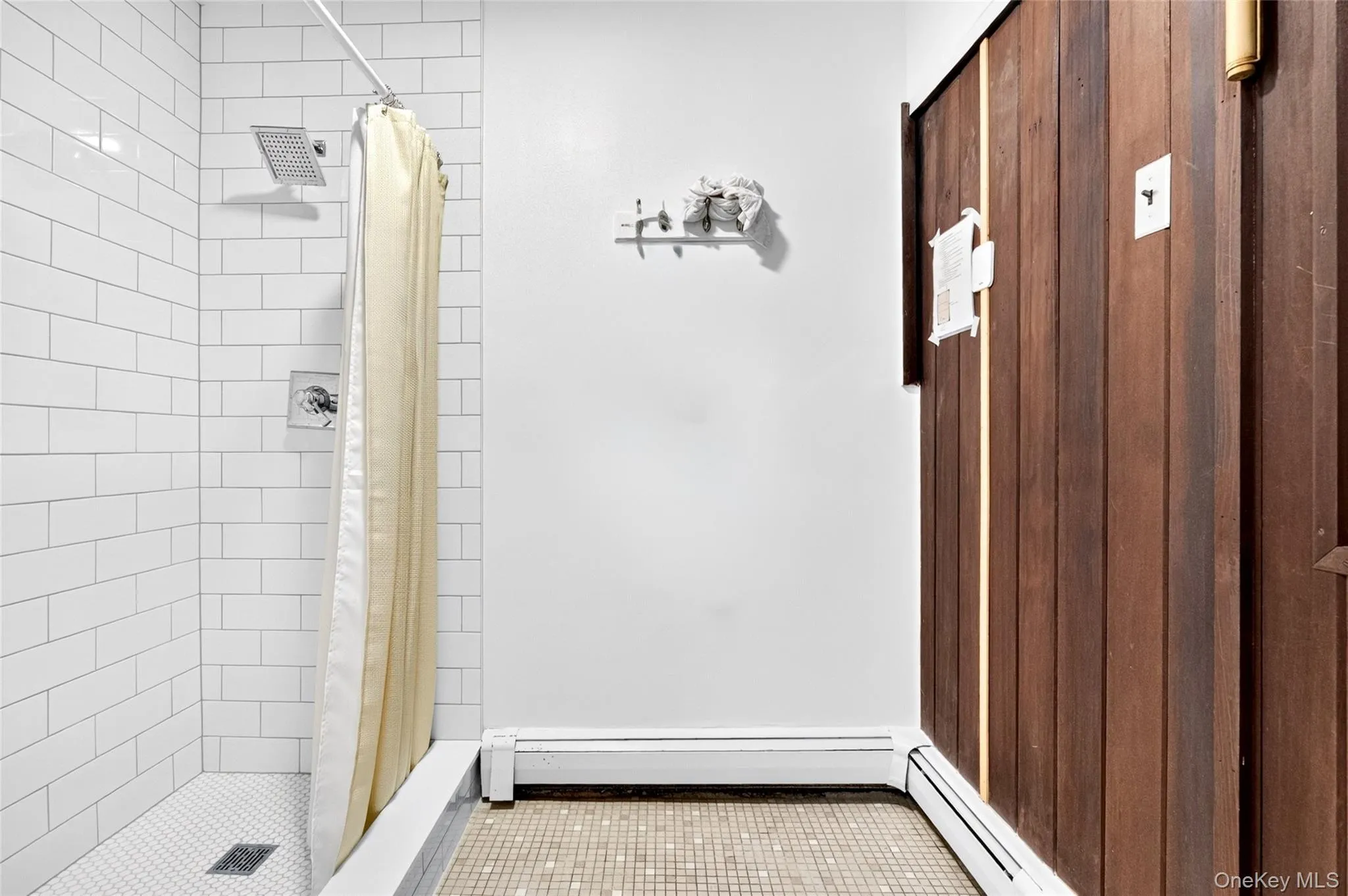 Shower with white subway tile surround, hexagonal mosaic floor, and rain shower head Shower with white subway tile surround, hexagonal mosaic floor, and rain shower head