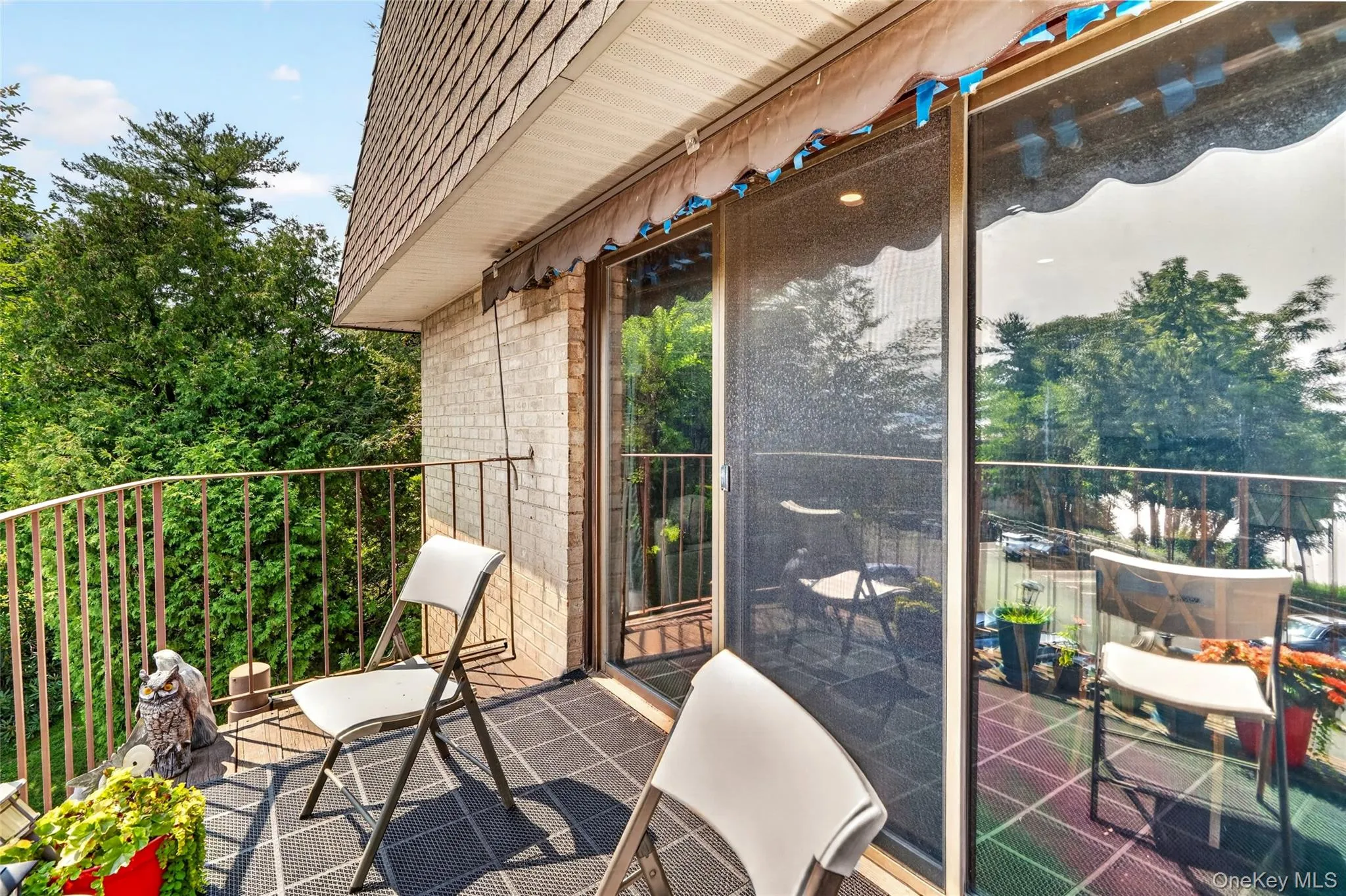 Balcony featuring a metal railing, brick exterior, patterned flooring, and a sliding glass door with an integrated screen Balcony featuring a metal railing, brick exterior, patterned flooring, and a sliding glass door with an integrated screen