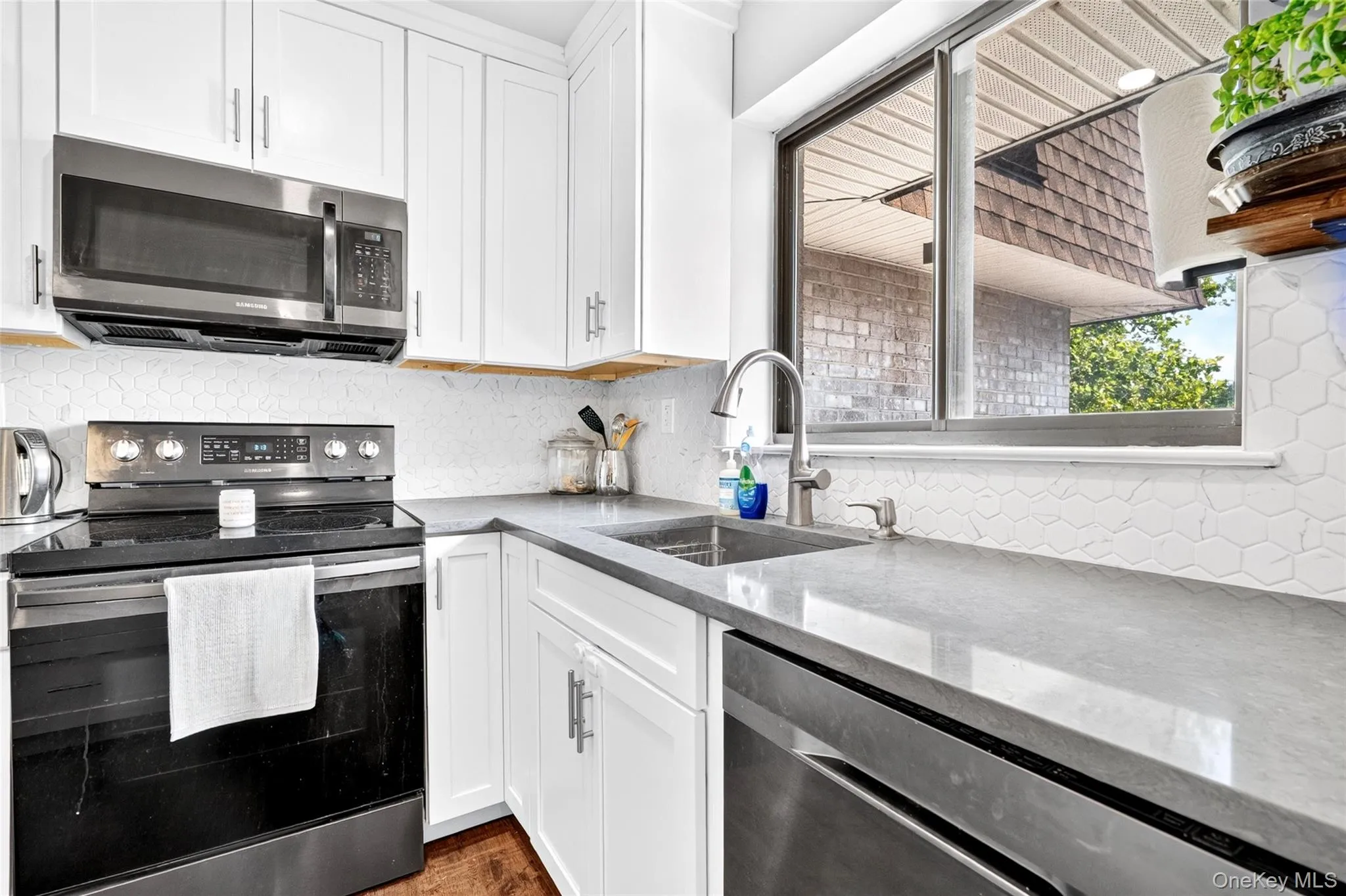 Contemporary kitchen featuring white cabinetry, a stainless steel over-the-range microwave, and a black electric range Contemporary kitchen featuring white cabinetry, a stainless steel over-the-range microwave, and a black electric range
