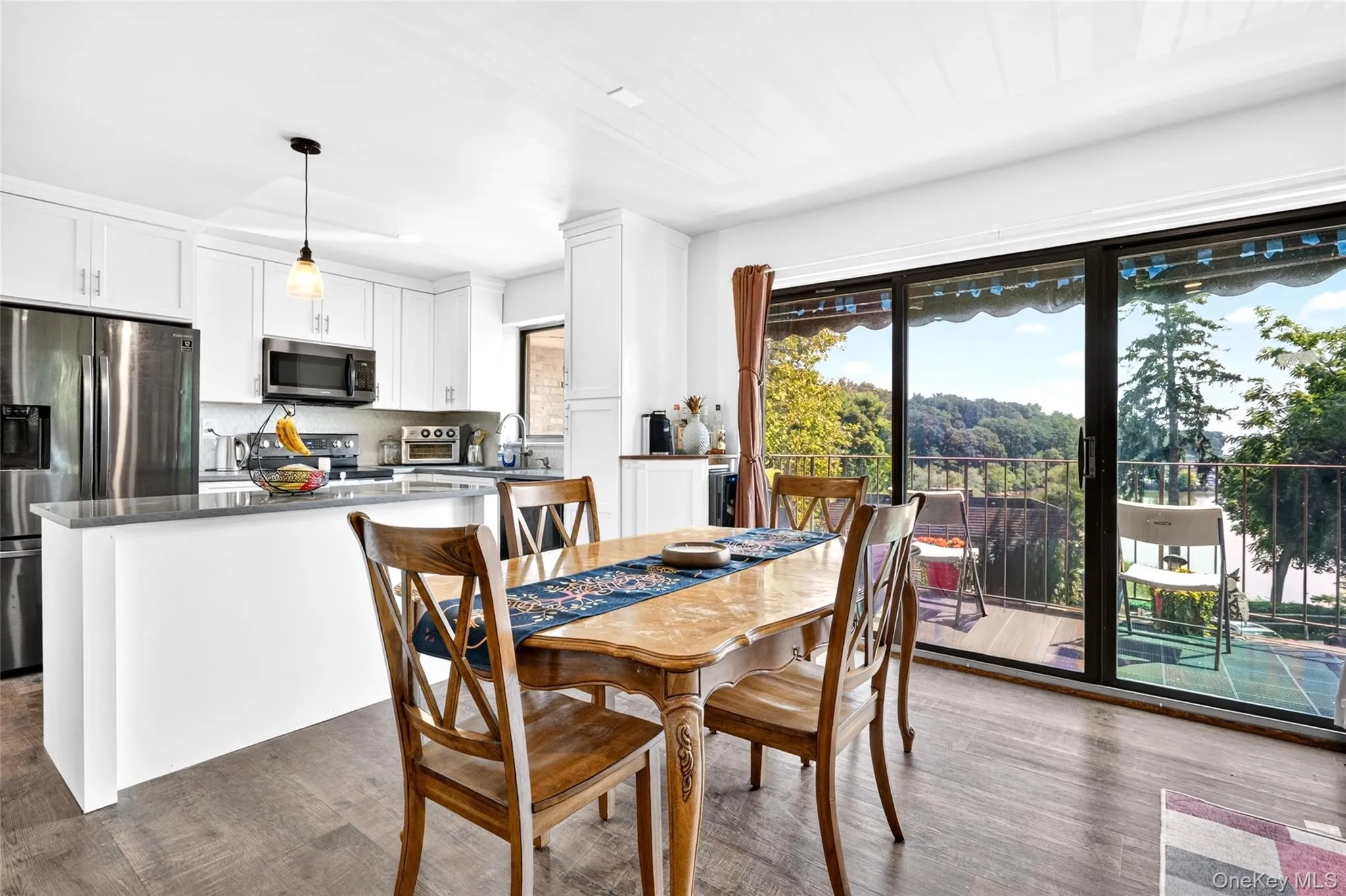 Open concept living space featuring a contemporary kitchen, wood-finish flooring, and a sliding glass door leading to a balcony Open concept living space featuring a contemporary kitchen, wood-finish flooring, and a sliding glass door leading to a balcony