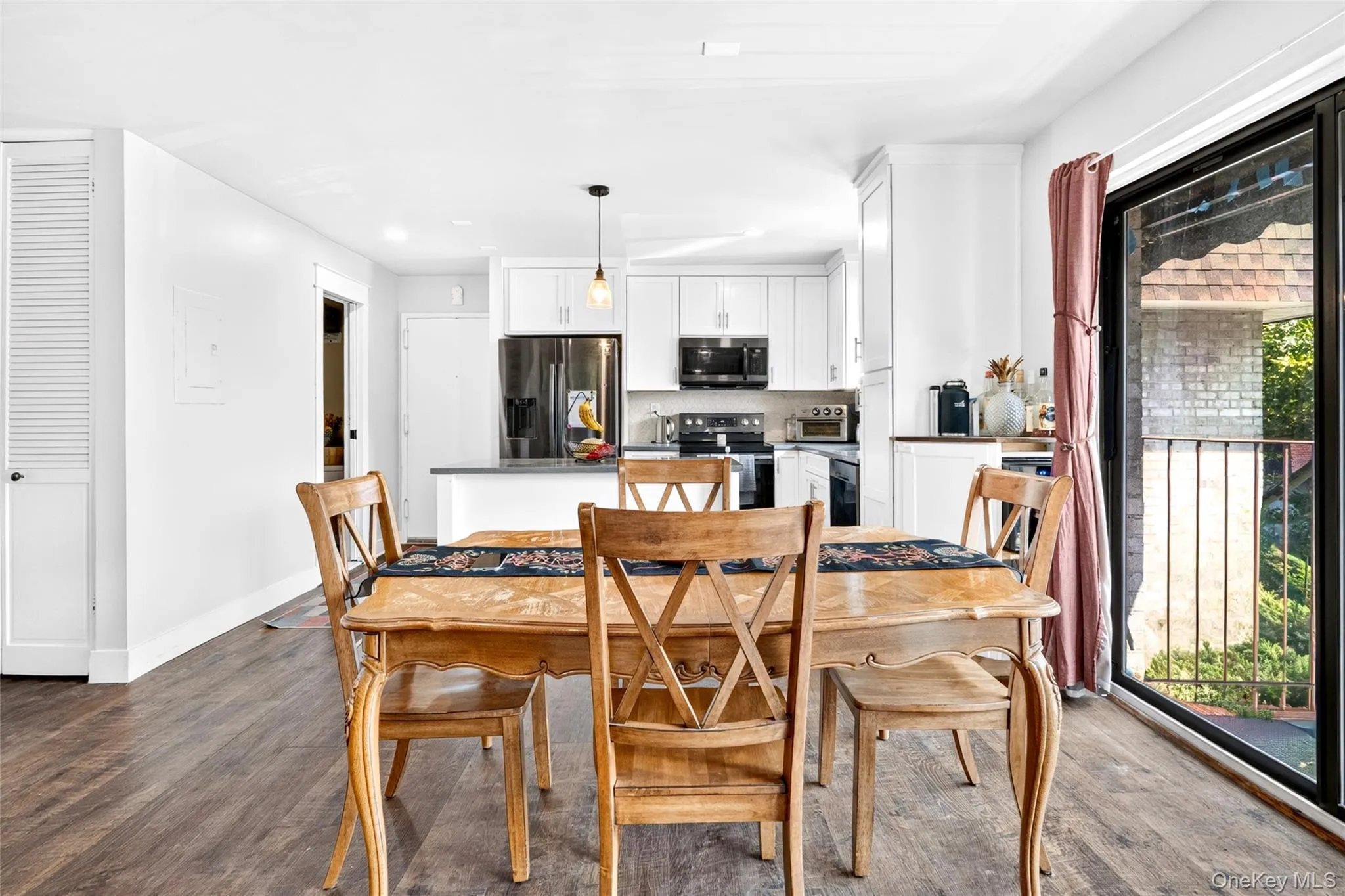 Spacious open-concept room featuring wood-finish flooring and a kitchen with white cabinetry Spacious open-concept room featuring wood-finish flooring and a kitchen with white cabinetry