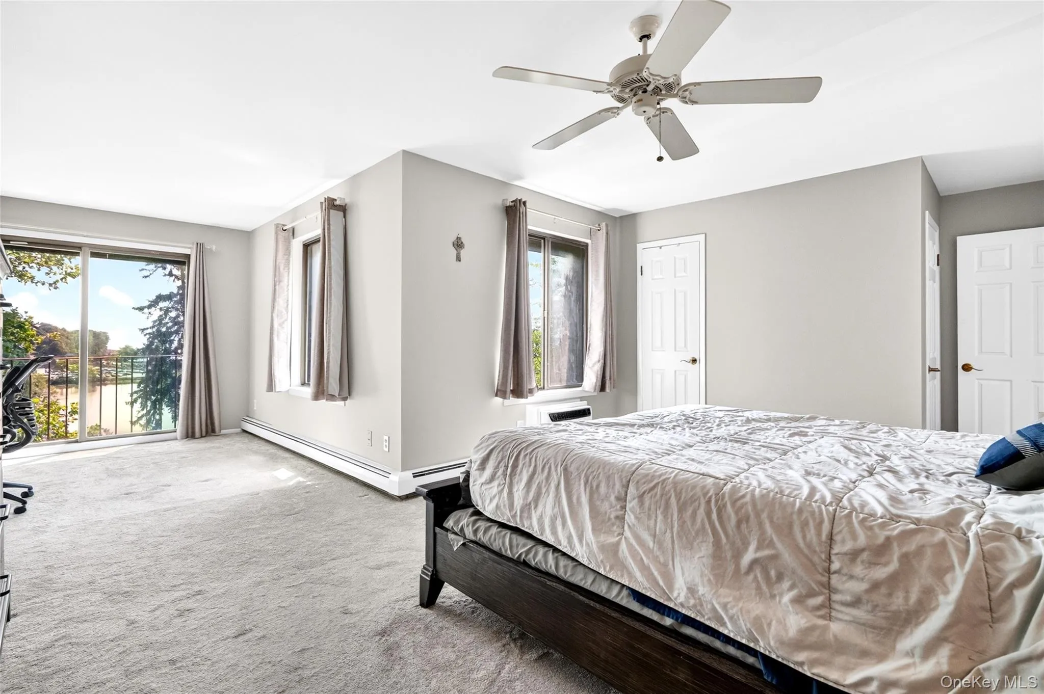 Spacious room with light gray walls, light-colored carpeting, a ceiling fan, and two interior doors Spacious room with light gray walls, light-colored carpeting, a ceiling fan, and two interior doors