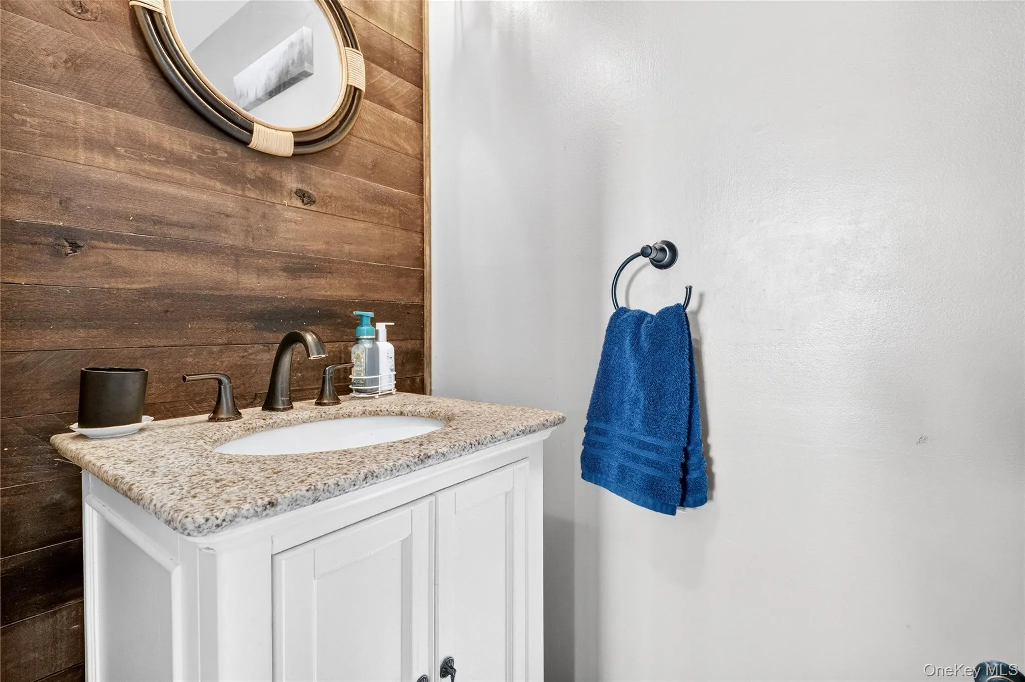 Bathroom vanity featuring a white cabinet, integrated sink, and a speckled countertop Bathroom vanity featuring a white cabinet, integrated sink, and a speckled countertop