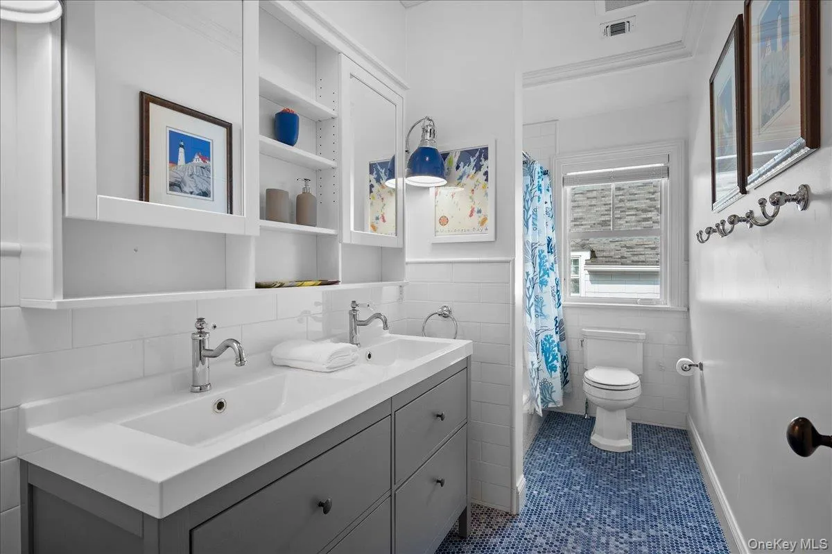Second level hall bathroom with double sink vanity and blue penny tile flooring. Second level hall bathroom with double sink vanity and blue penny tile flooring.