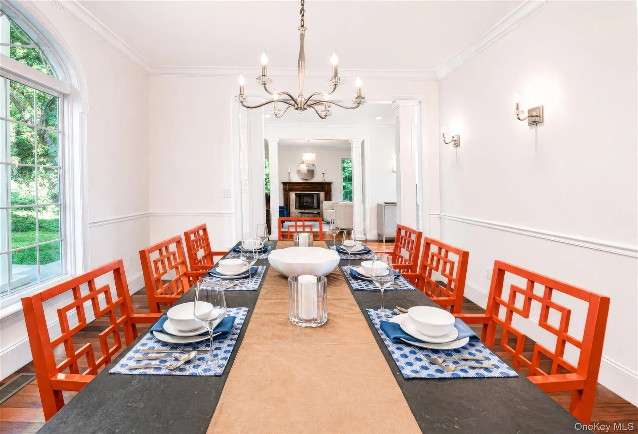 The warm and inviting dining room is filled with natural sunlight through elegant windows and enhanced by refined architectural details, including chair rail and crown moldings, a statement chandelier, and classic wall sconces. The warm and inviting dining room is filled with natural sunlight through elegant windows and enhanced by refined architectural details, including chair rail and crown moldings, a statement chandelier, and classic wall sconces.