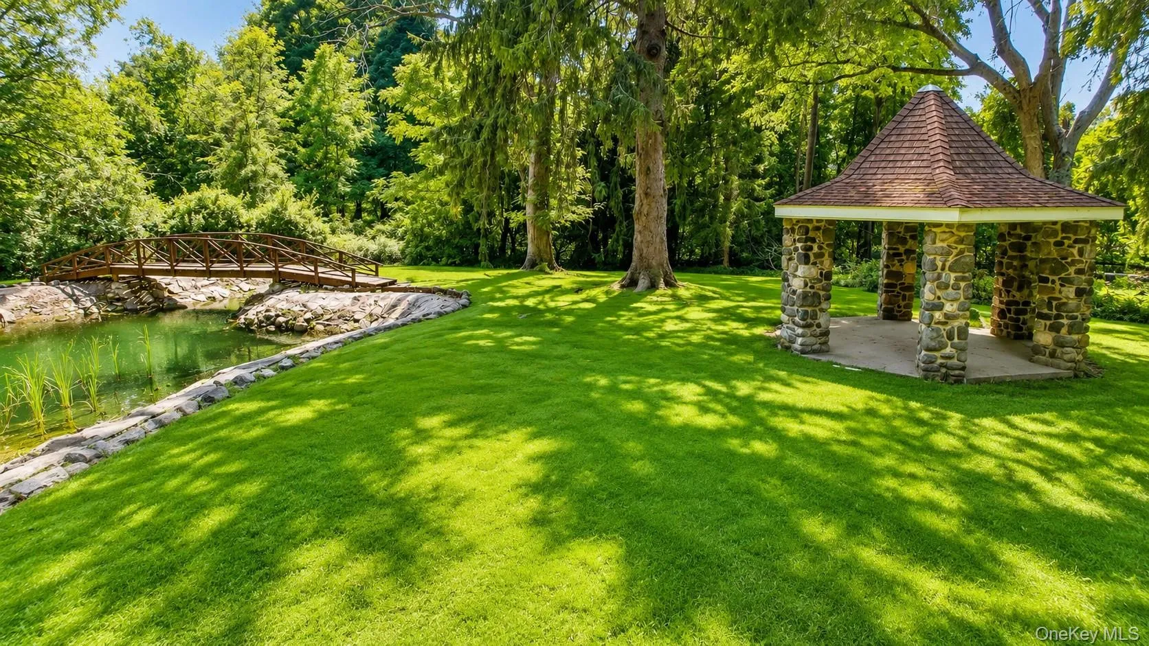 Storybook grounds unfold with winding walkways, a charming gazebo, tranquil pond, and picturesque kissing bridge—creating an enchanting setting for unforgettable gatherings and entertaining. Storybook grounds unfold with winding walkways, a charming gazebo, tranquil pond, and picturesque kissing bridge—creating an enchanting setting for unforgettable gatherings and entertaining.