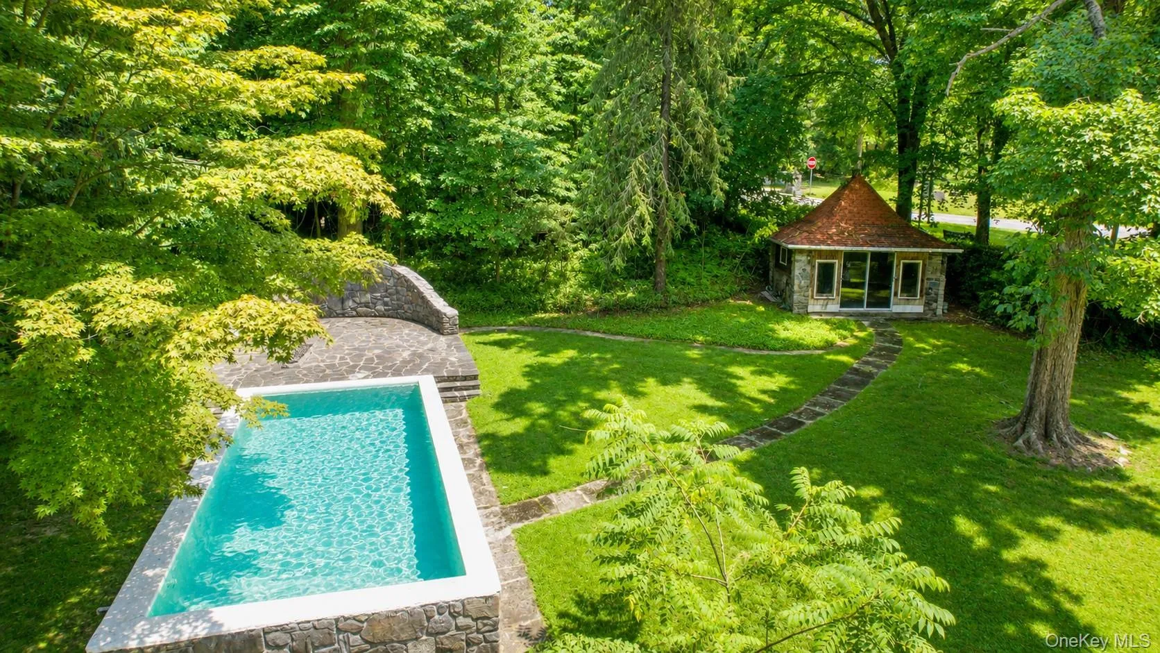 A true storybook setting awaits, featuring a stunning stone-faced pool, expansive patio, and pool house—the perfect outdoor retreat for relaxing and entertaining. A true storybook setting awaits, featuring a stunning stone-faced pool, expansive patio, and pool house—the perfect outdoor retreat for relaxing and entertaining.