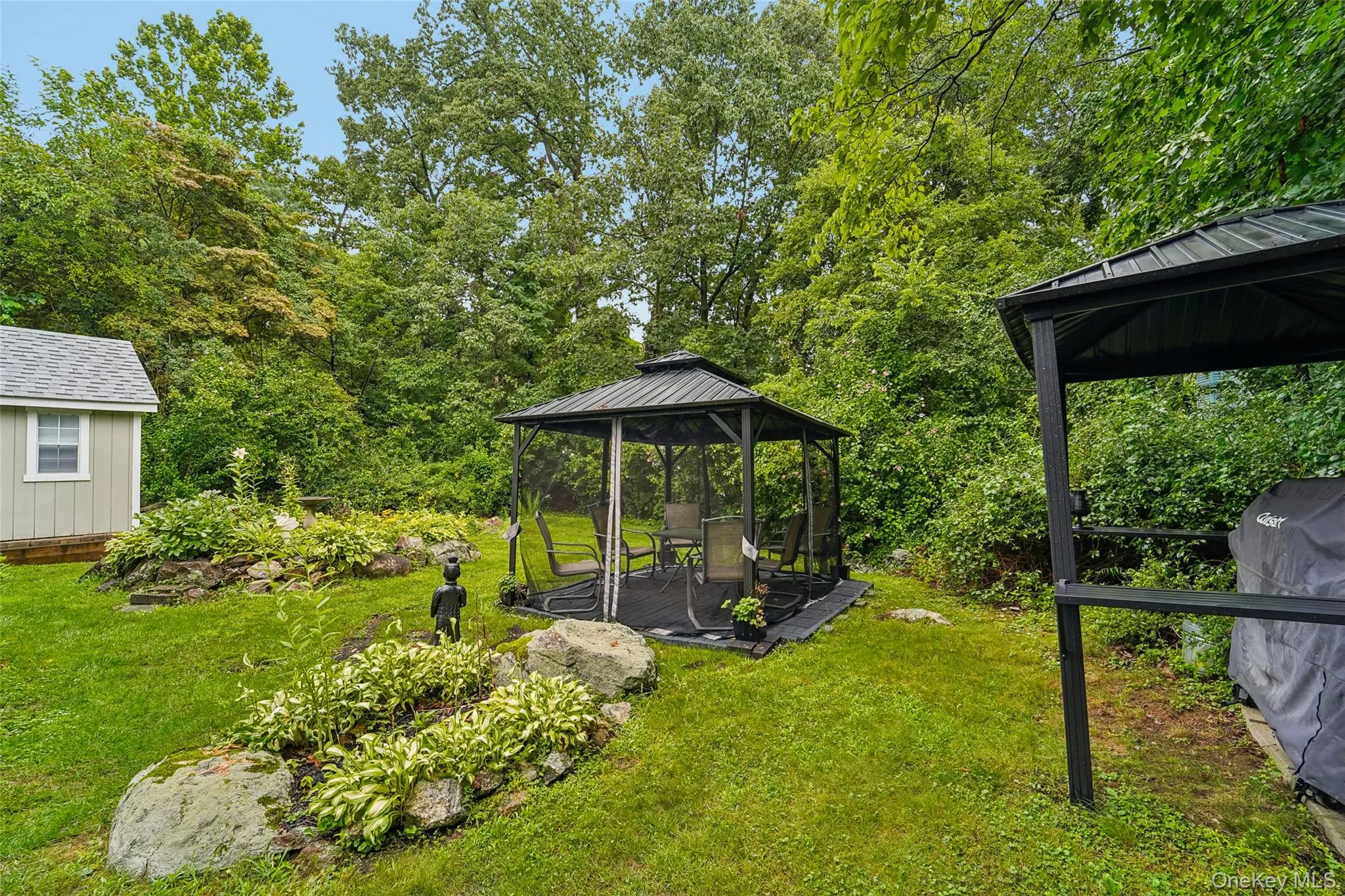 Backyard showing landscaping, finished shed, covered grill space, and screened hardtop gazebo. Backyard showing landscaping, finished shed, covered grill space, and screened hardtop gazebo.
