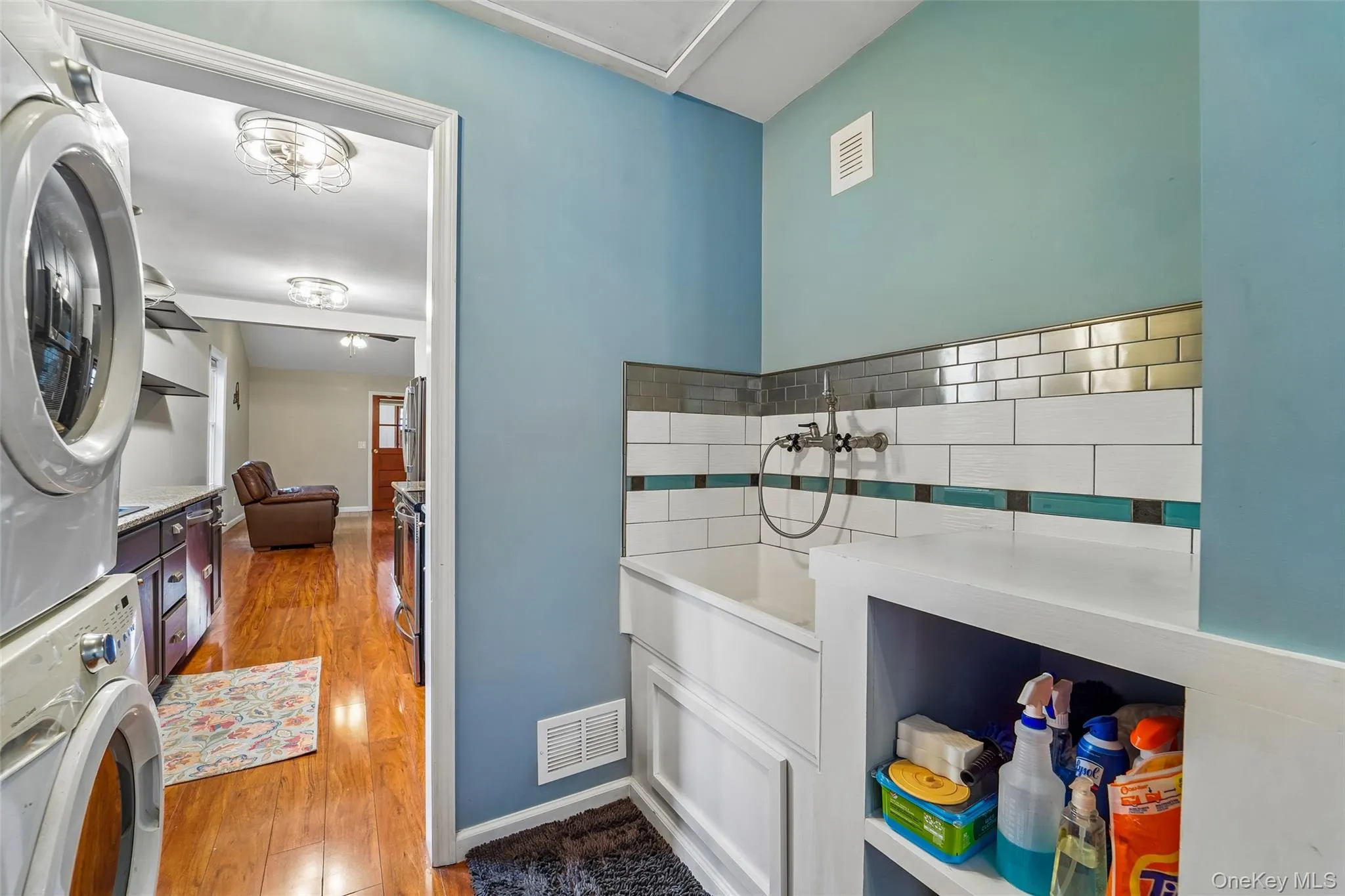 Stacked laundry area with utility sink and storage. Stacked laundry area with utility sink and storage.