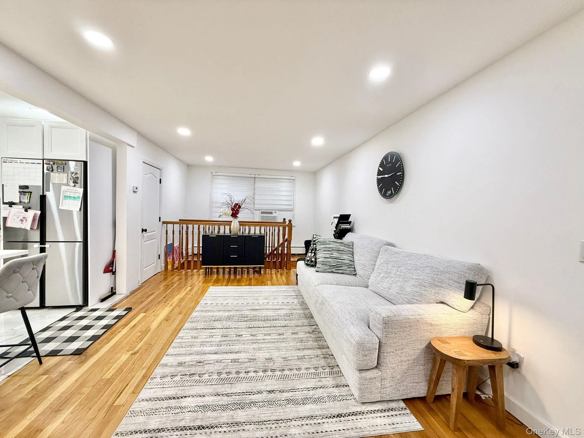Bright living area featuring wood-finish flooring, recessed lighting, and white walls Bright living area featuring wood-finish flooring, recessed lighting, and white walls