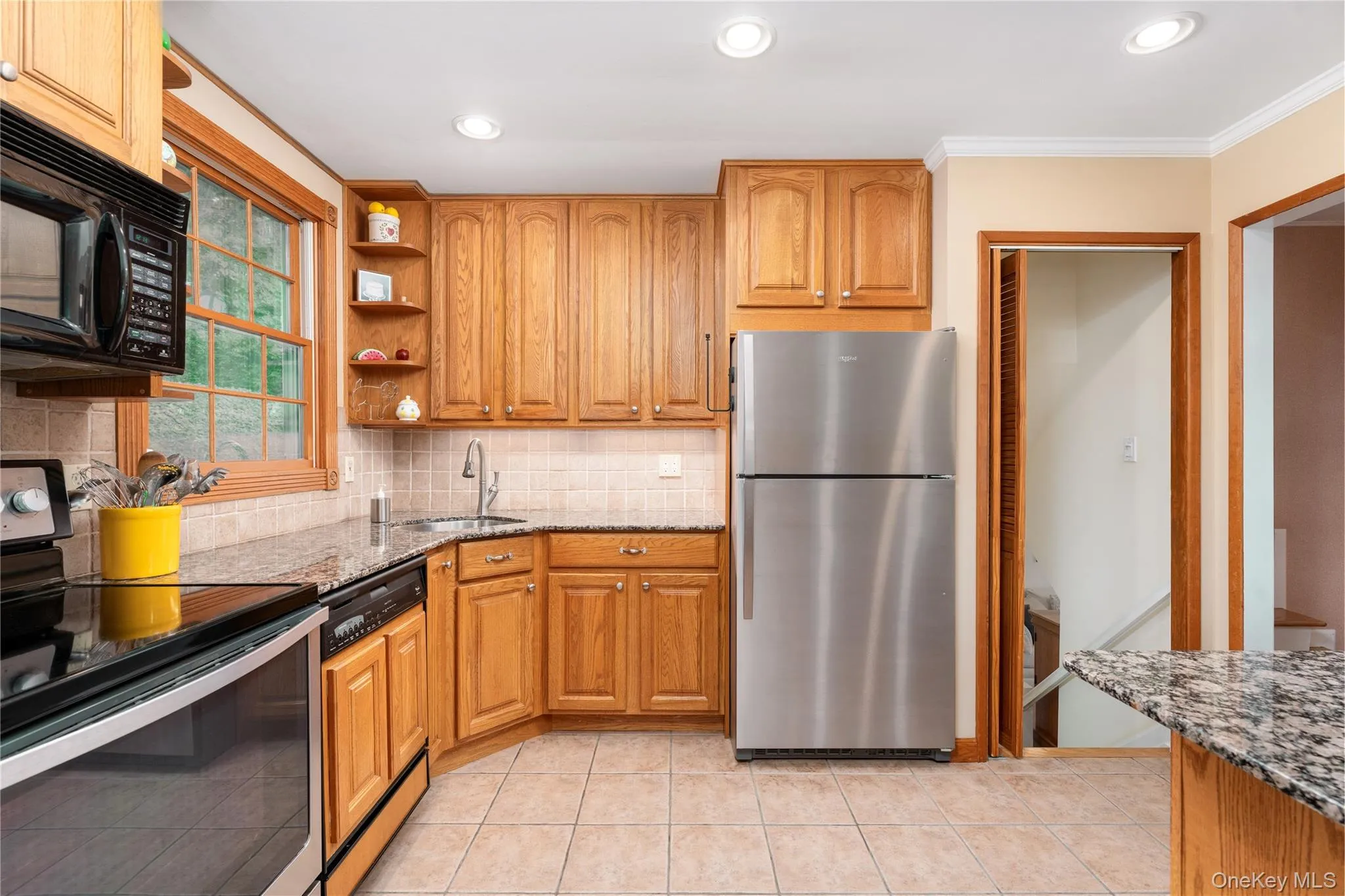 Kitchen featuring solid wood cabinetry, stainless steel appliances, granite countertops, and tiled flooring Kitchen featuring solid wood cabinetry, stainless steel appliances, granite countertops, and tiled flooring
