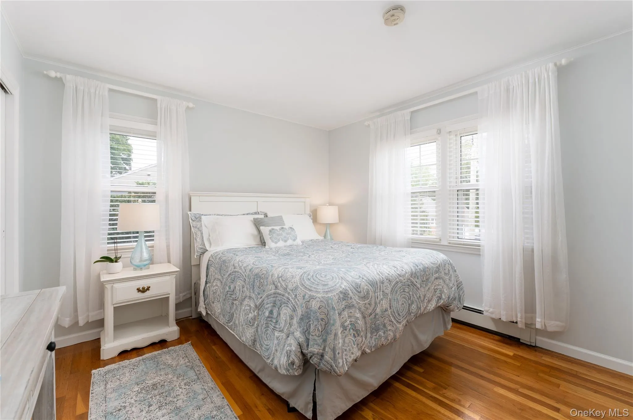Wood-finish flooring, white window blinds, and multiple windows Wood-finish flooring, white window blinds, and multiple windows