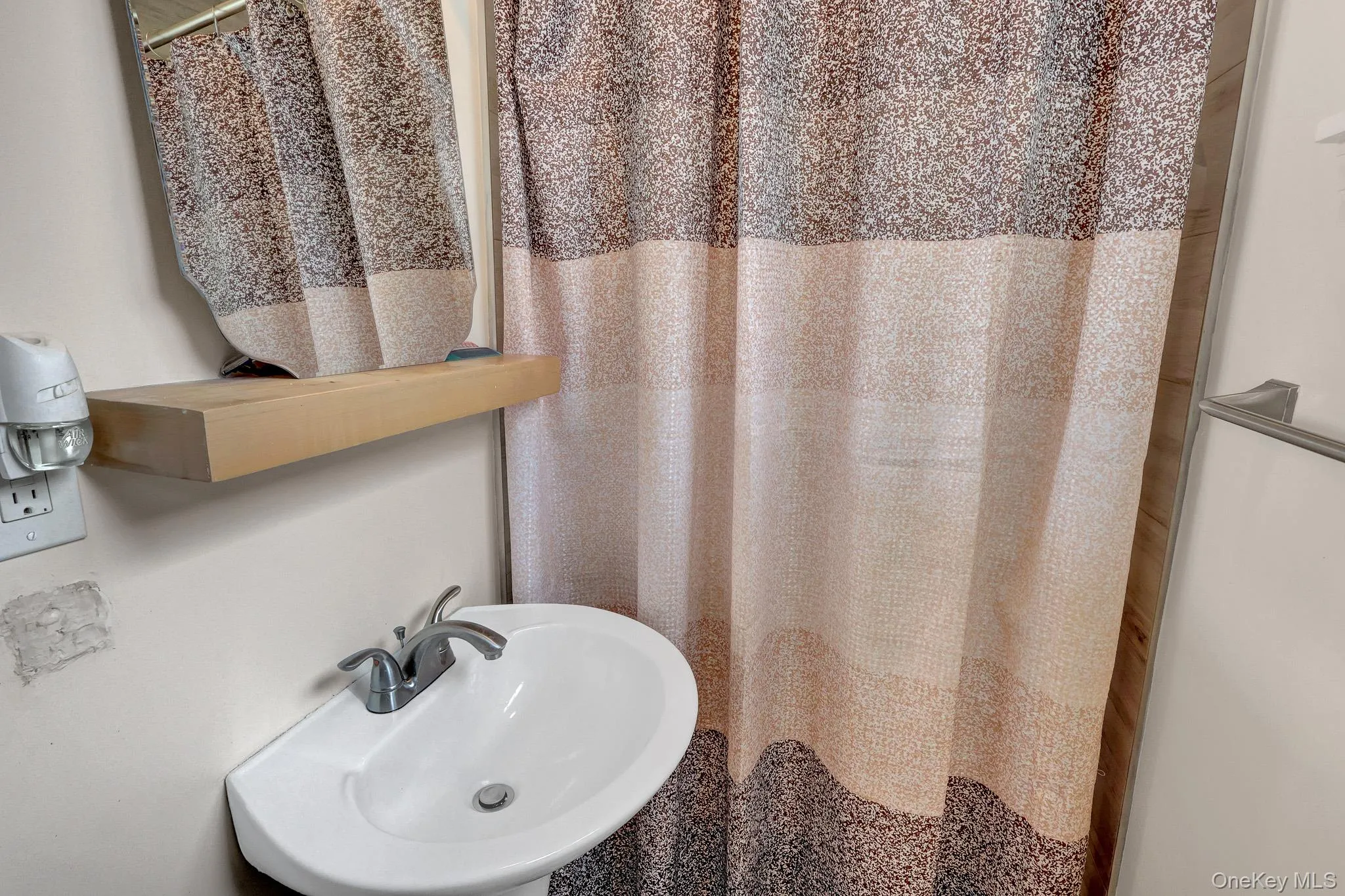 Pedestal sink with chrome faucet, complemented by a wall-mounted mirror and light-toned floating shelf Pedestal sink with chrome faucet, complemented by a wall-mounted mirror and light-toned floating shelf