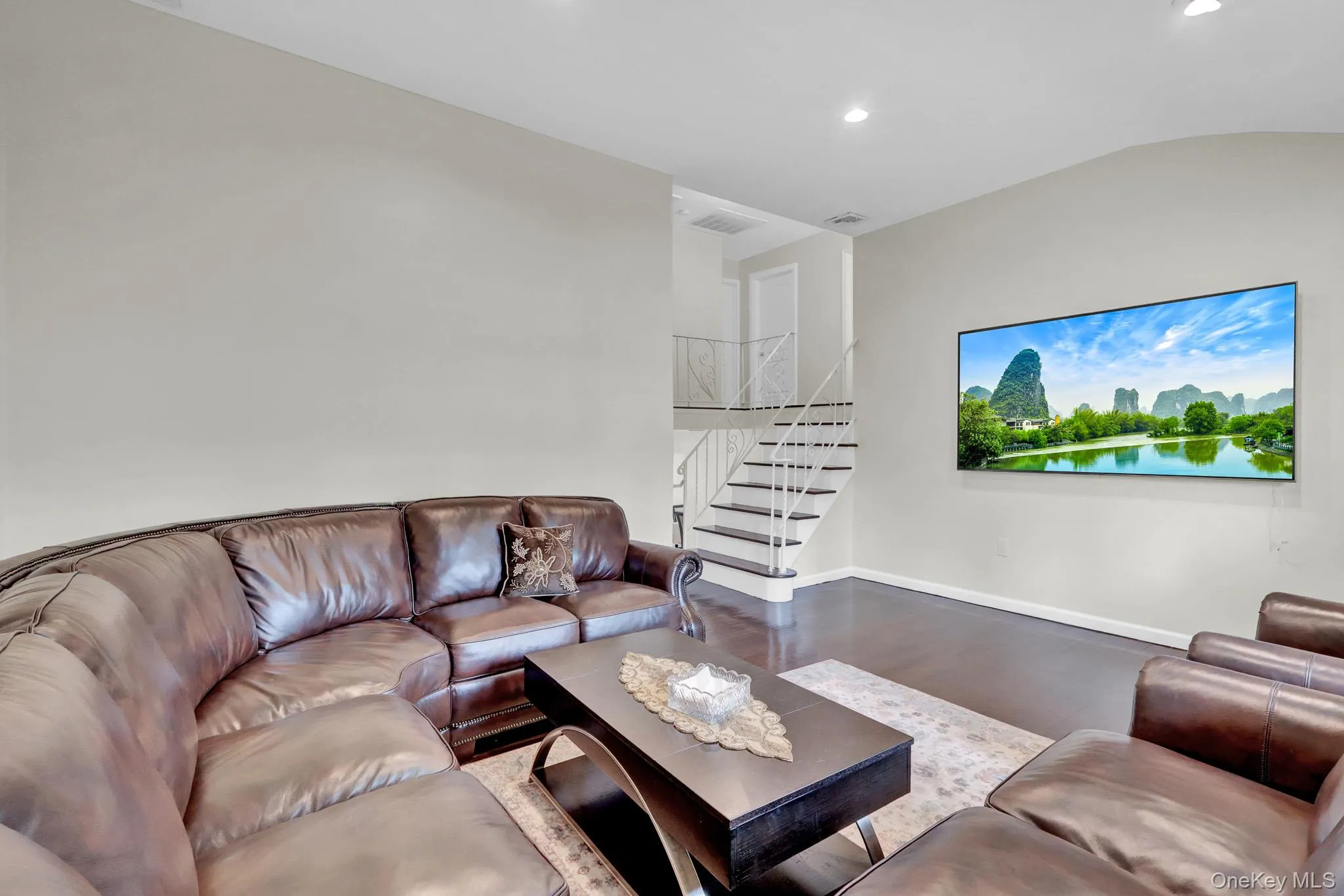 Living area featuring dark wood-finish flooring, recessed lighting, and light-toned walls Living area featuring dark wood-finish flooring, recessed lighting, and light-toned walls