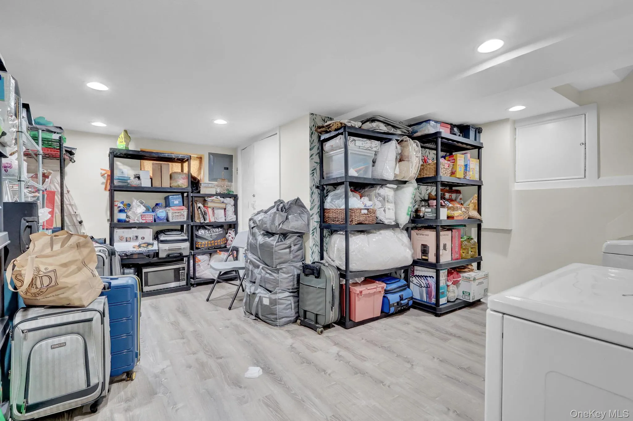 Spacious utility area featuring light wood-finish flooring, recessed lighting, and a white washer unit Spacious utility area featuring light wood-finish flooring, recessed lighting, and a white washer unit