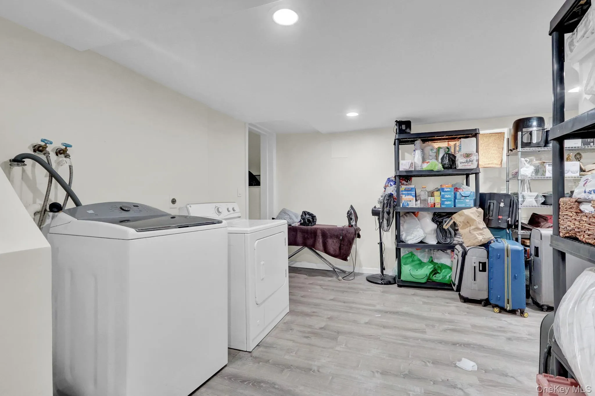 Laundry area featuring light wood-finish flooring, recessed lighting, and ample storage space Laundry area featuring light wood-finish flooring, recessed lighting, and ample storage space