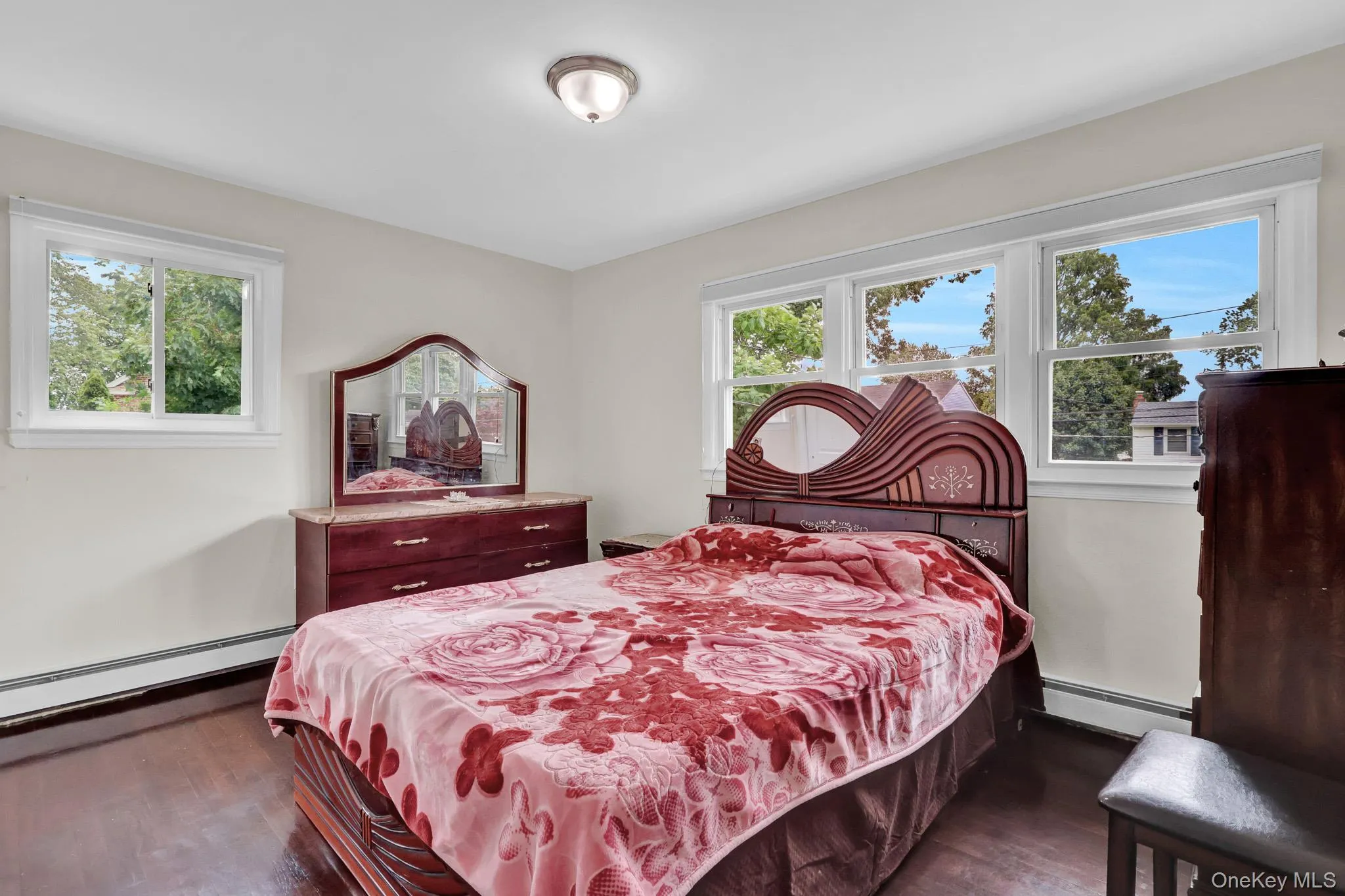 Bright room featuring multiple windows, wood-finish flooring, a neutral wall palette, and a semi-flush mount ceiling light fixture Bright room featuring multiple windows, wood-finish flooring, a neutral wall palette, and a semi-flush mount ceiling light fixture