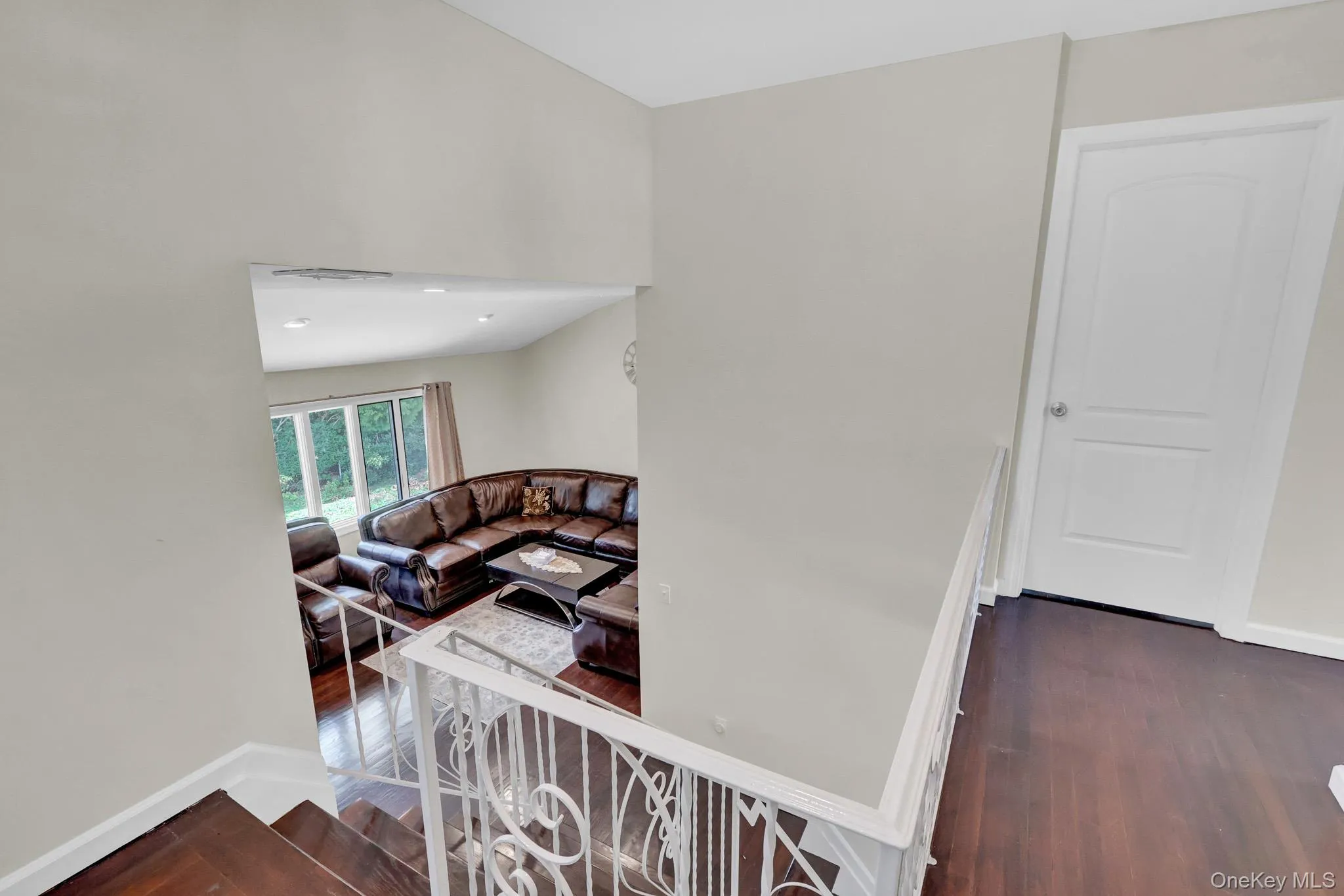 Hardwood flooring throughout, with a white ornate metal railing Hardwood flooring throughout, with a white ornate metal railing