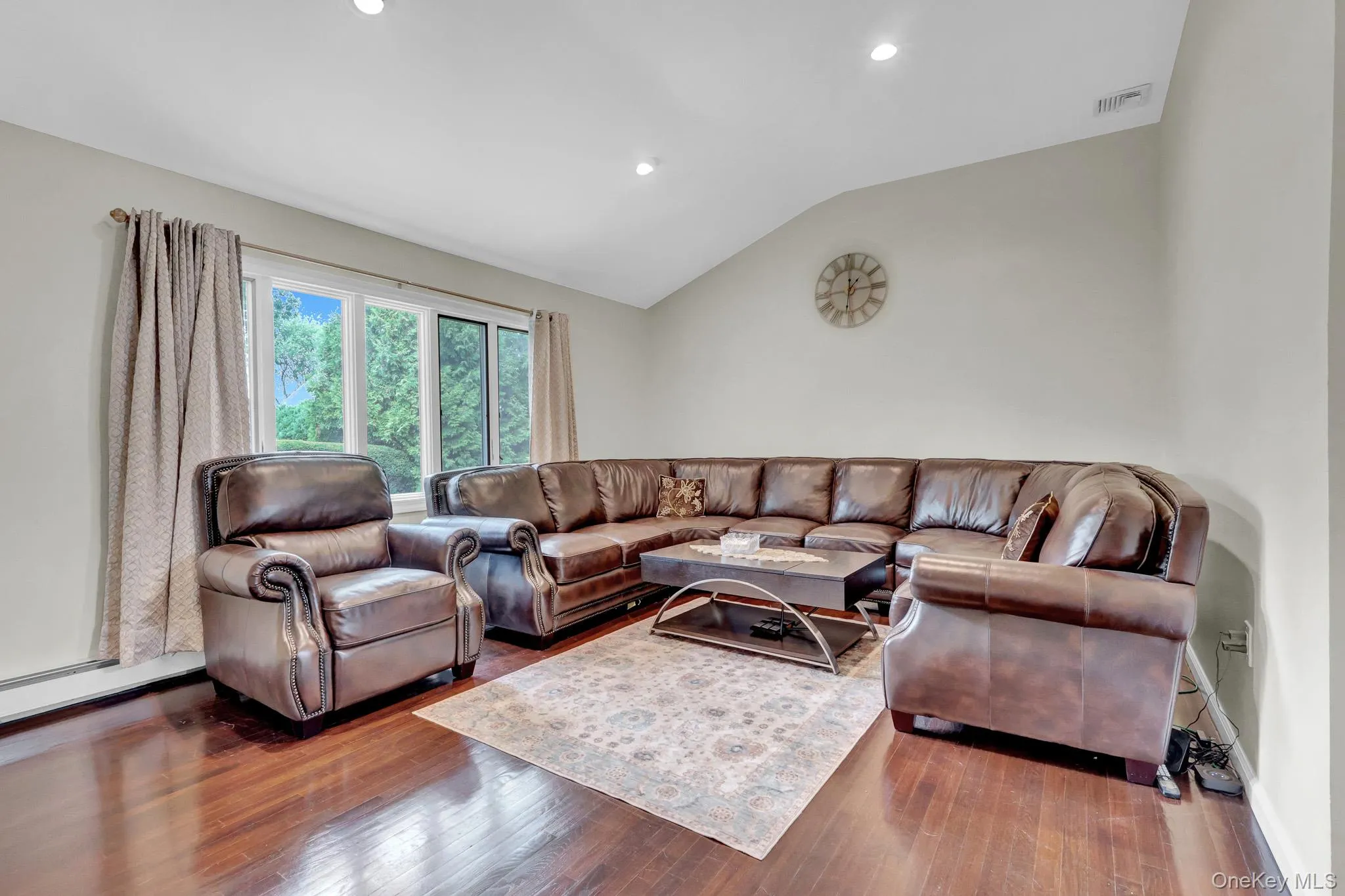Spacious room featuring rich wood-finish flooring and a vaulted ceiling Spacious room featuring rich wood-finish flooring and a vaulted ceiling
