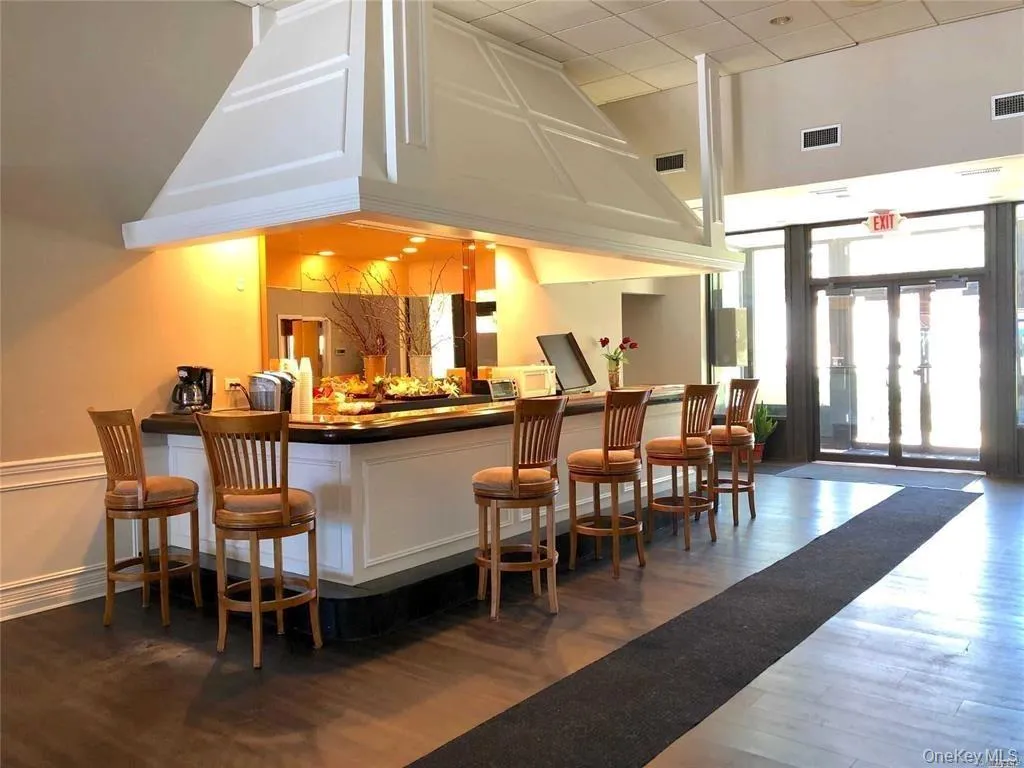 Indoor dry bar with dark wood finished floors, dark countertops, white cabinetry, and floor to ceiling windows Indoor dry bar with dark wood finished floors, dark countertops, white cabinetry, and floor to ceiling windows