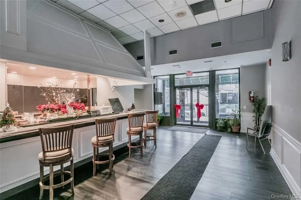 Community lobby featuring a decorative wall, wainscoting, a drop ceiling, and expansive windows Community lobby featuring a decorative wall, wainscoting, a drop ceiling, and expansive windows