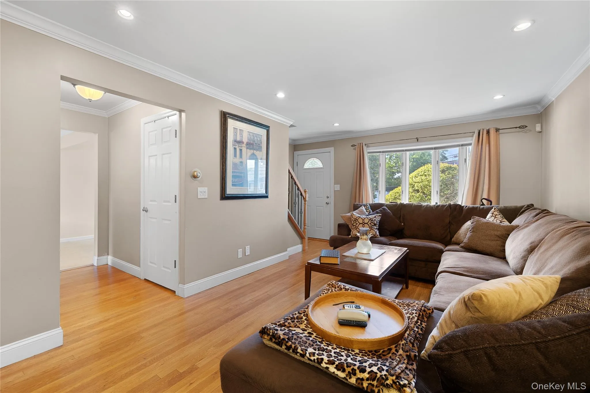 Living area featuring hardwood flooring, recessed lighting, crown molding, and a large bay window Living area featuring hardwood flooring, recessed lighting, crown molding, and a large bay window
