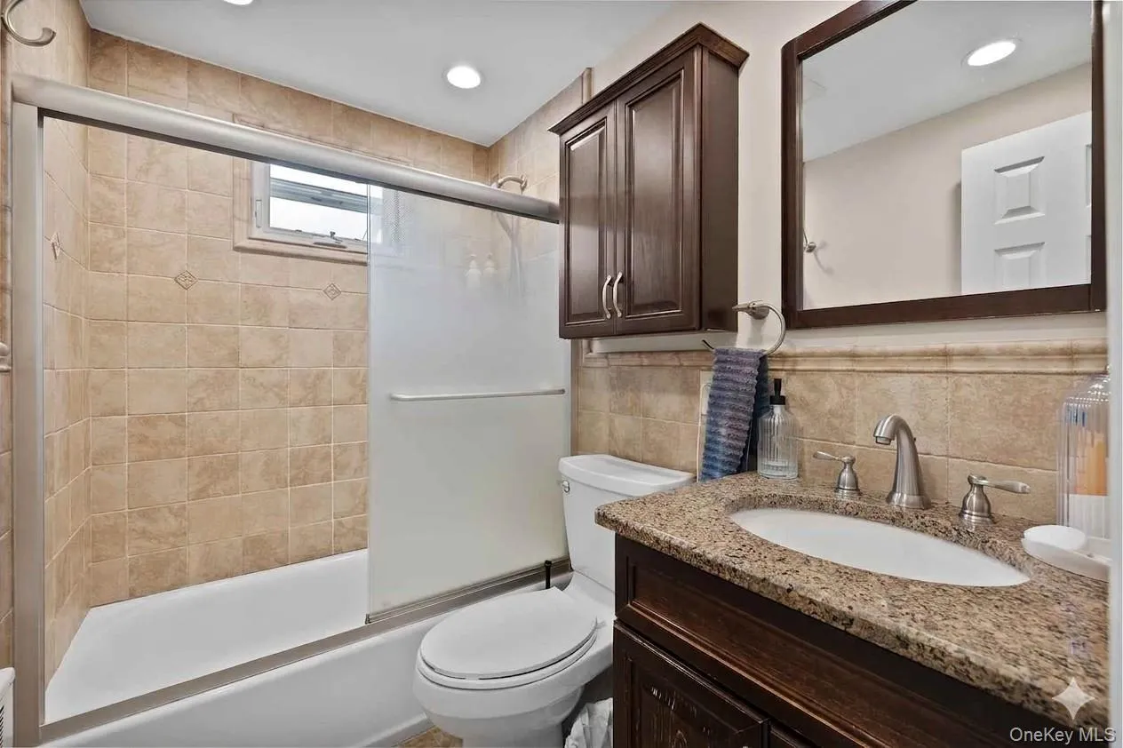 Bathroom featuring a tub with sliding frosted glass enclosure and a small window. Bathroom featuring a tub with sliding frosted glass enclosure and a small window.
