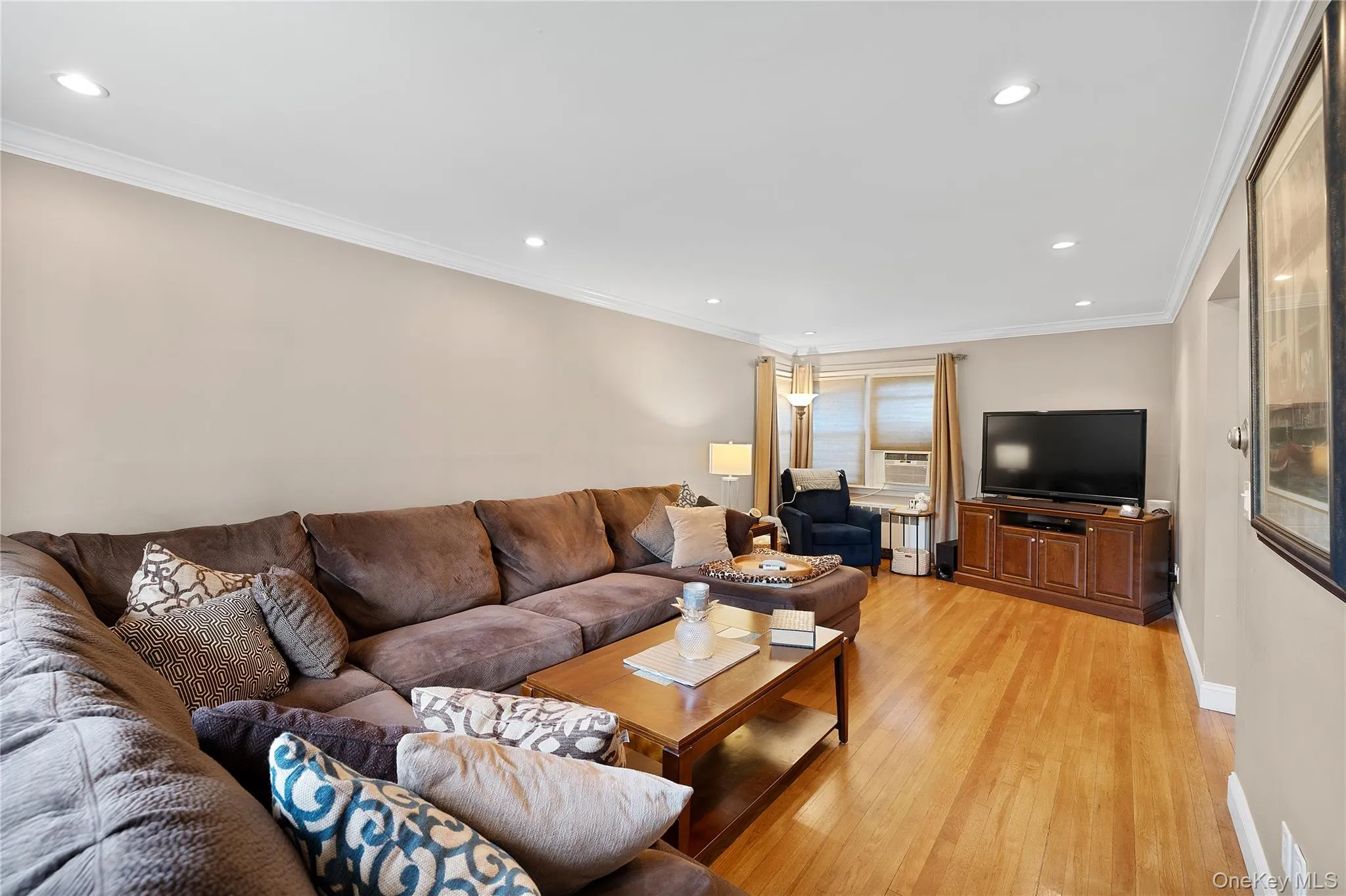Living area featuring wood-finish flooring, recessed lighting, and crown molding Living area featuring wood-finish flooring, recessed lighting, and crown molding