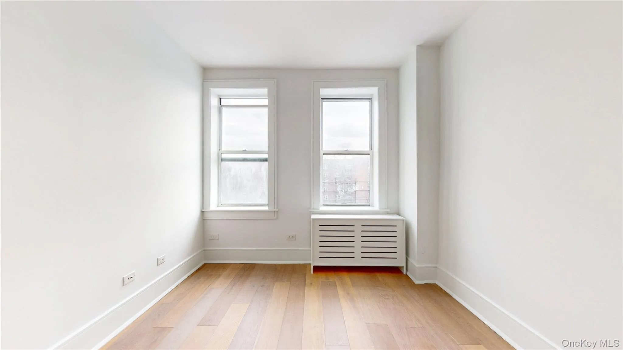 Room featuring wood-finish flooring and bright white walls Room featuring wood-finish flooring and bright white walls