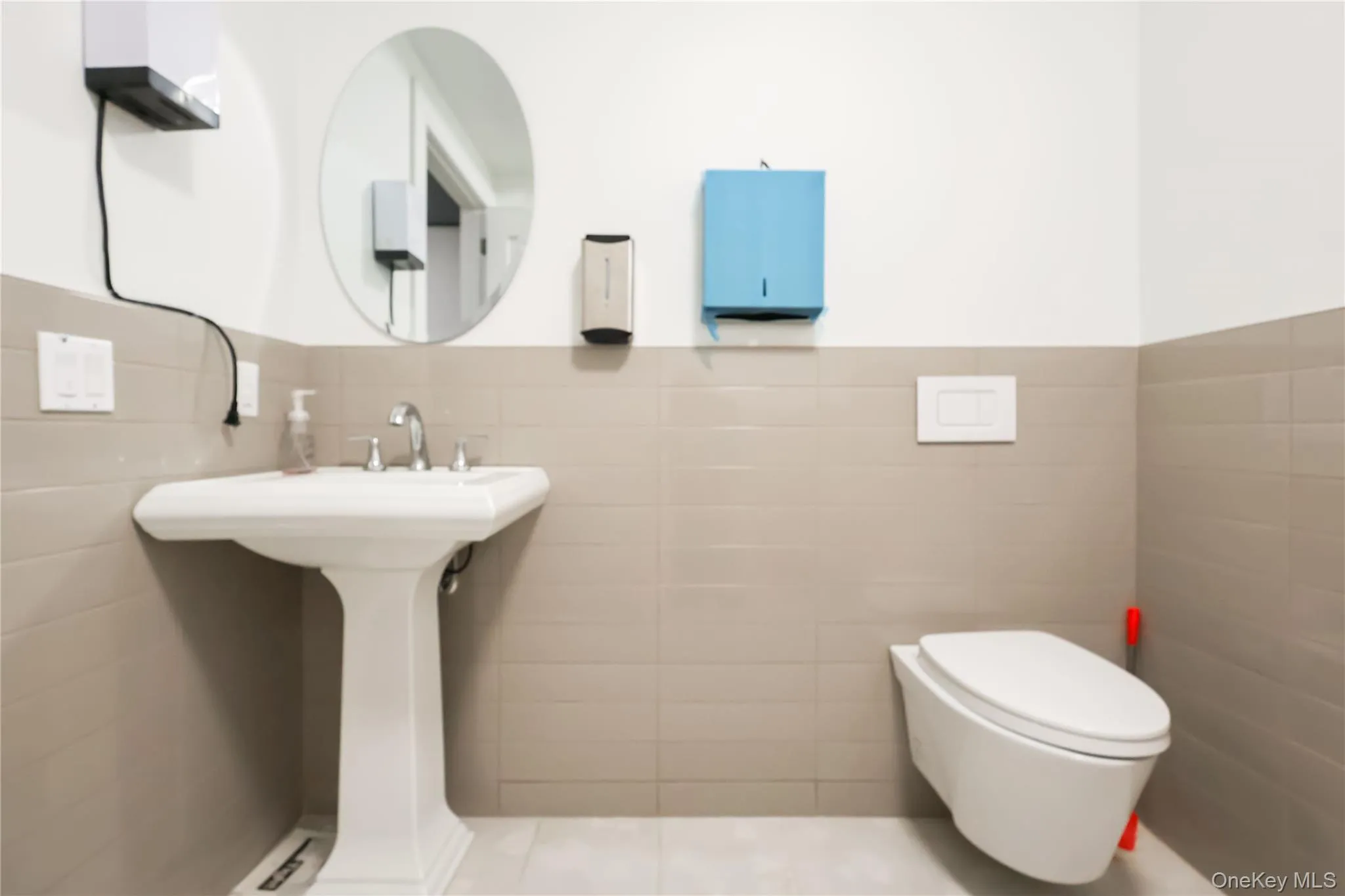 Pedestal sink with chrome fixtures and an oval wall mirror Pedestal sink with chrome fixtures and an oval wall mirror