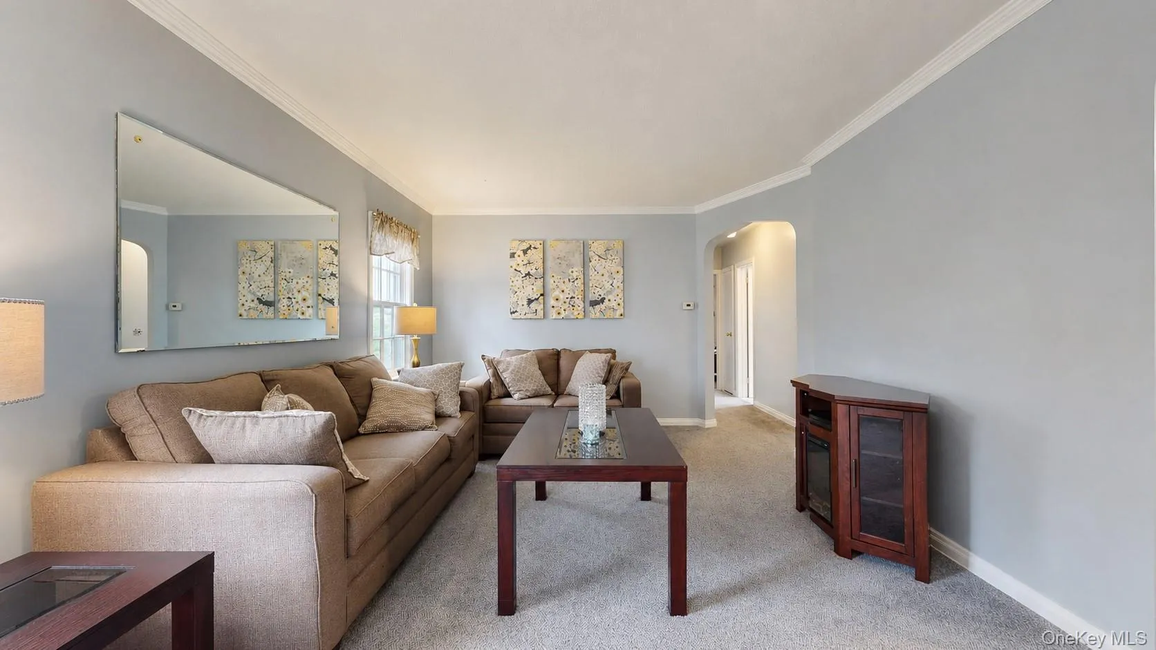 Living room featuring light gray walls, white crown molding, and gray carpeting Living room featuring light gray walls, white crown molding, and gray carpeting