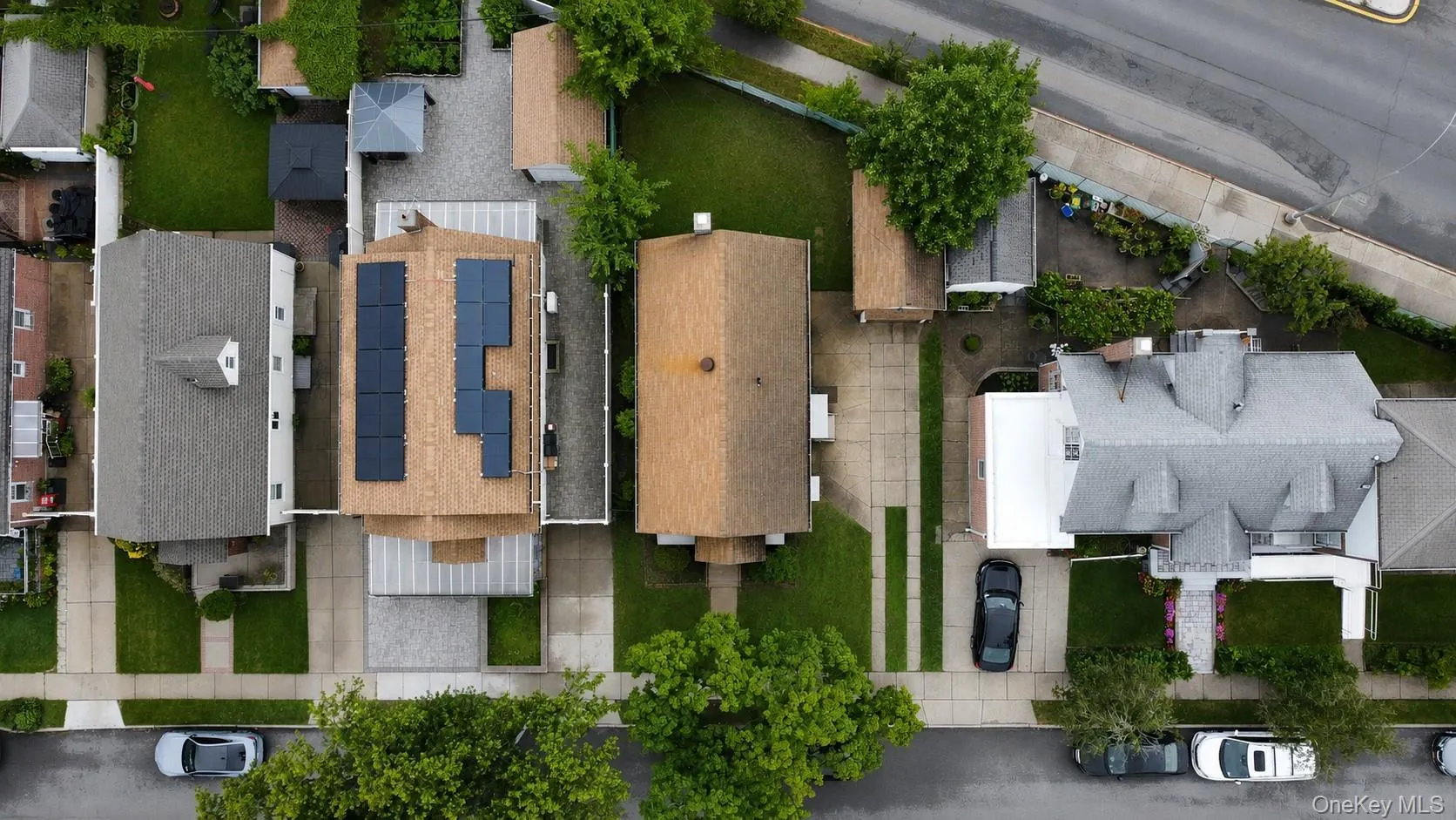 Gable roof residence with solar panel array, paved driveway, and established green lawn Gable roof residence with solar panel array, paved driveway, and established green lawn