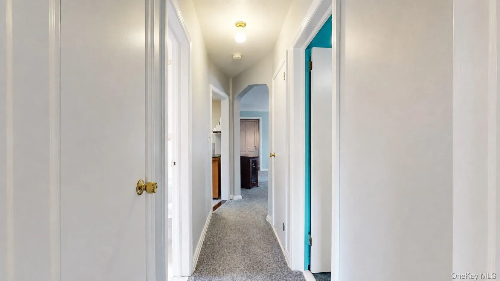 Hallway featuring light gray walls, gray carpet flooring, and white trim Hallway featuring light gray walls, gray carpet flooring, and white trim
