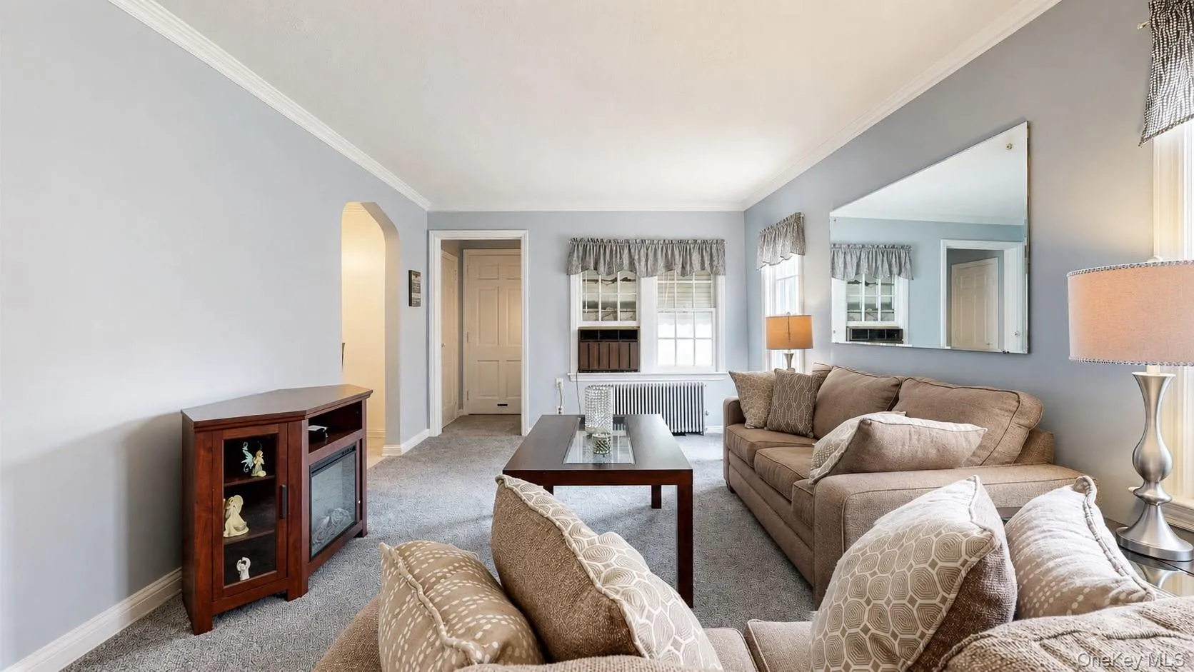 Living room featuring light blue walls, grey carpet flooring, white baseboards, and white crown molding Living room featuring light blue walls, grey carpet flooring, white baseboards, and white crown molding
