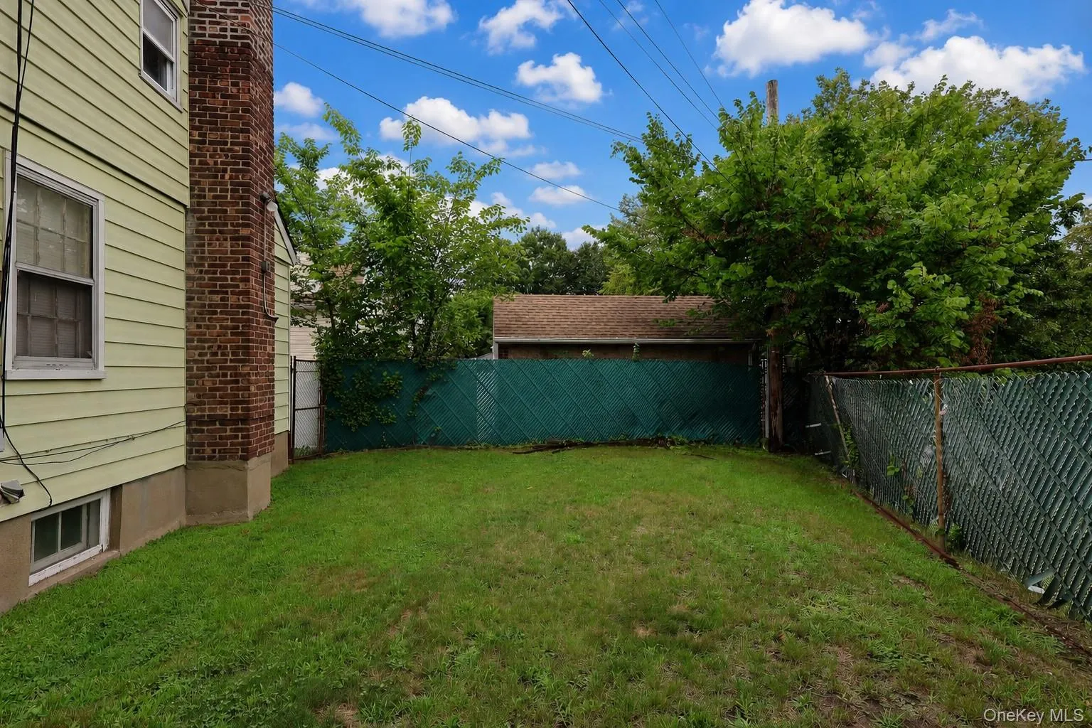 Spacious backyard featuring a manicured lawn, brick chimney exterior, and privacy fencing Spacious backyard featuring a manicured lawn, brick chimney exterior, and privacy fencing