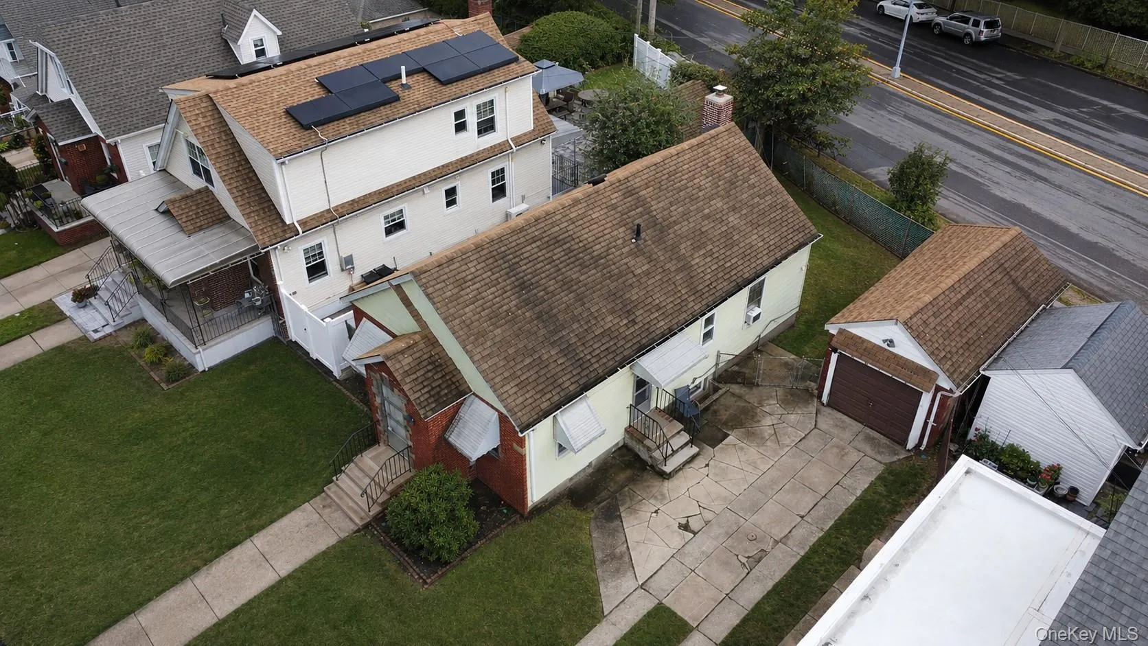 Aerial perspective showcasing a property with a detached garage and paved driveway Aerial perspective showcasing a property with a detached garage and paved driveway