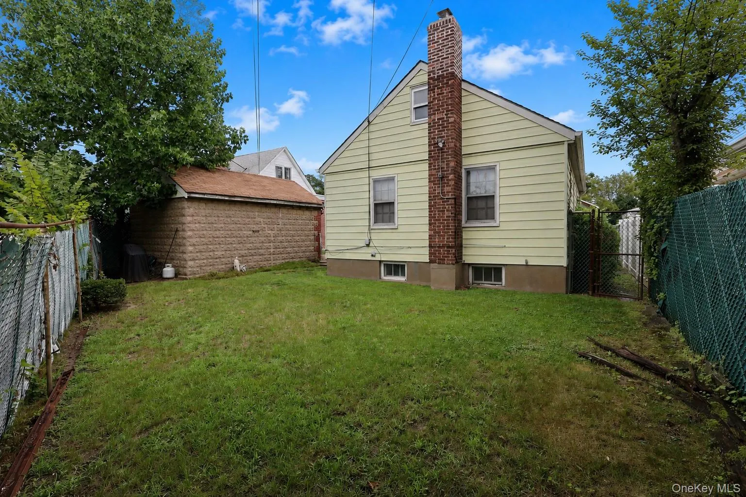 Rear exterior featuring siding, brick chimney, and a detached structure with a pitched roof Rear exterior featuring siding, brick chimney, and a detached structure with a pitched roof