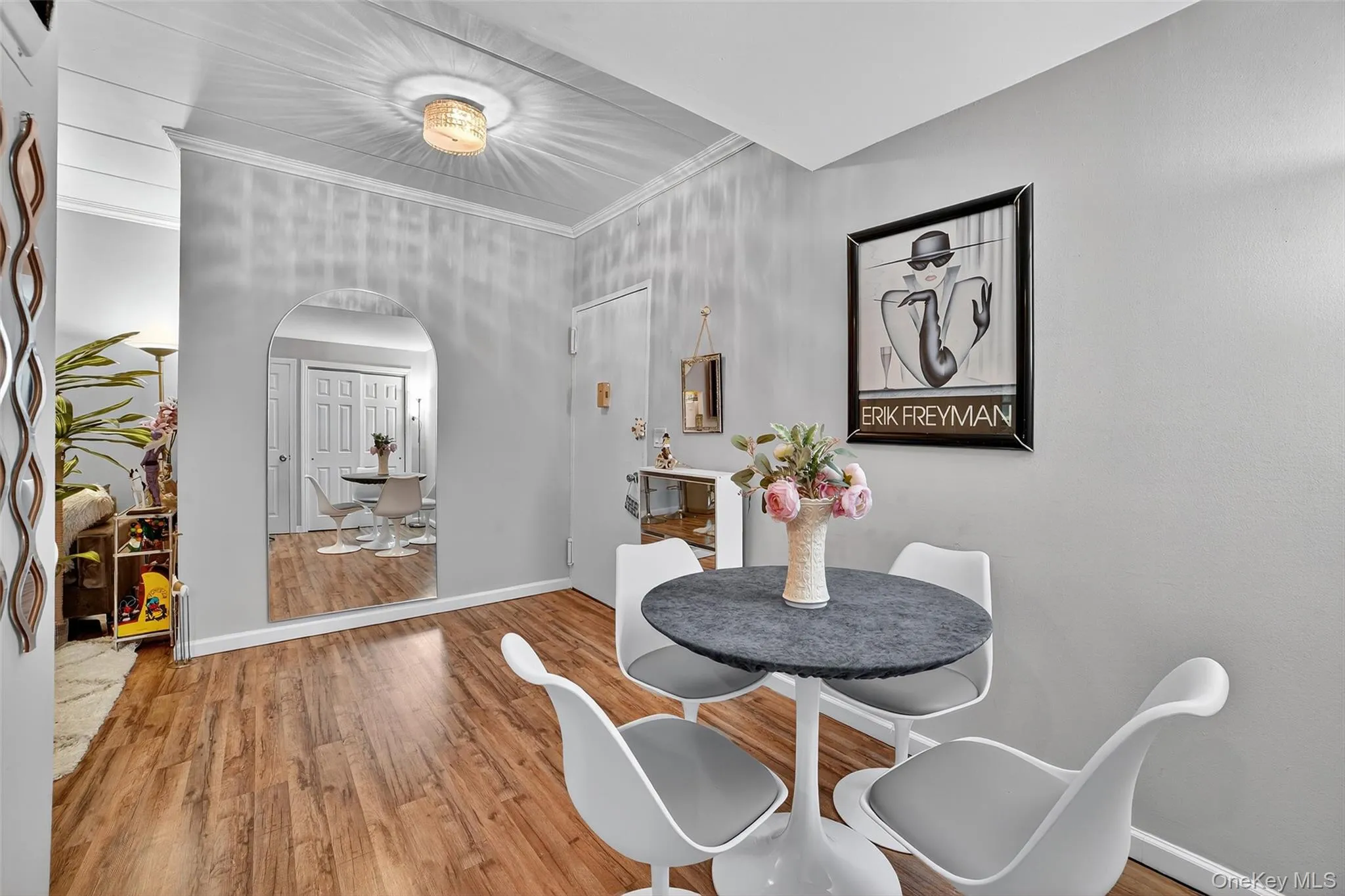 Dining room with light wood-style flooring, crown molding, and arched walkways Dining room with light wood-style flooring, crown molding, and arched walkways