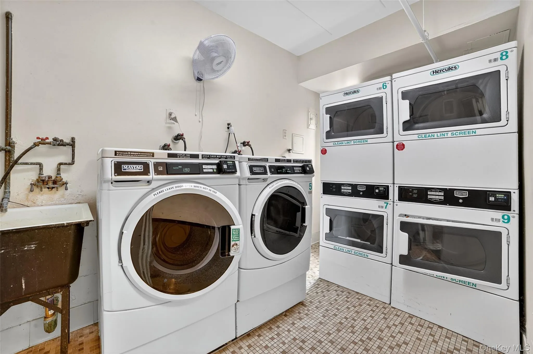 Communal laundry room with light tile patterned floors, washer and dryer, and stacked washer / dryer Communal laundry room with light tile patterned floors, washer and dryer, and stacked washer / dryer