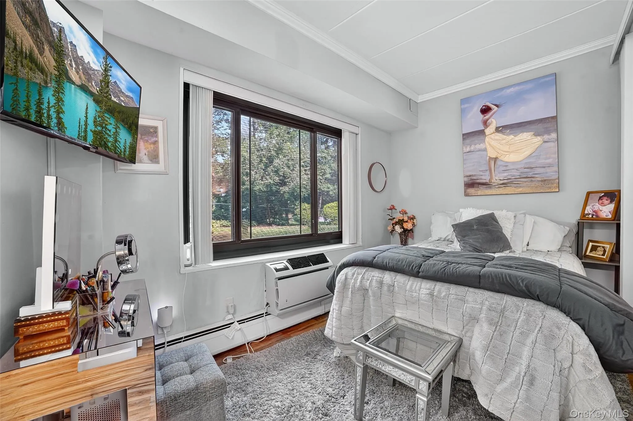 Bedroom featuring ornamental molding, a baseboard heating unit, and wood finished floors Bedroom featuring ornamental molding, a baseboard heating unit, and wood finished floors