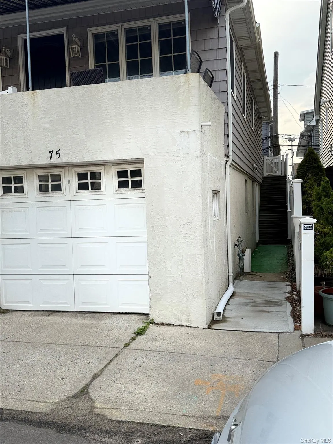 View of side of property featuring stucco siding, stairs, and an attached garage View of side of property featuring stucco siding, stairs, and an attached garage