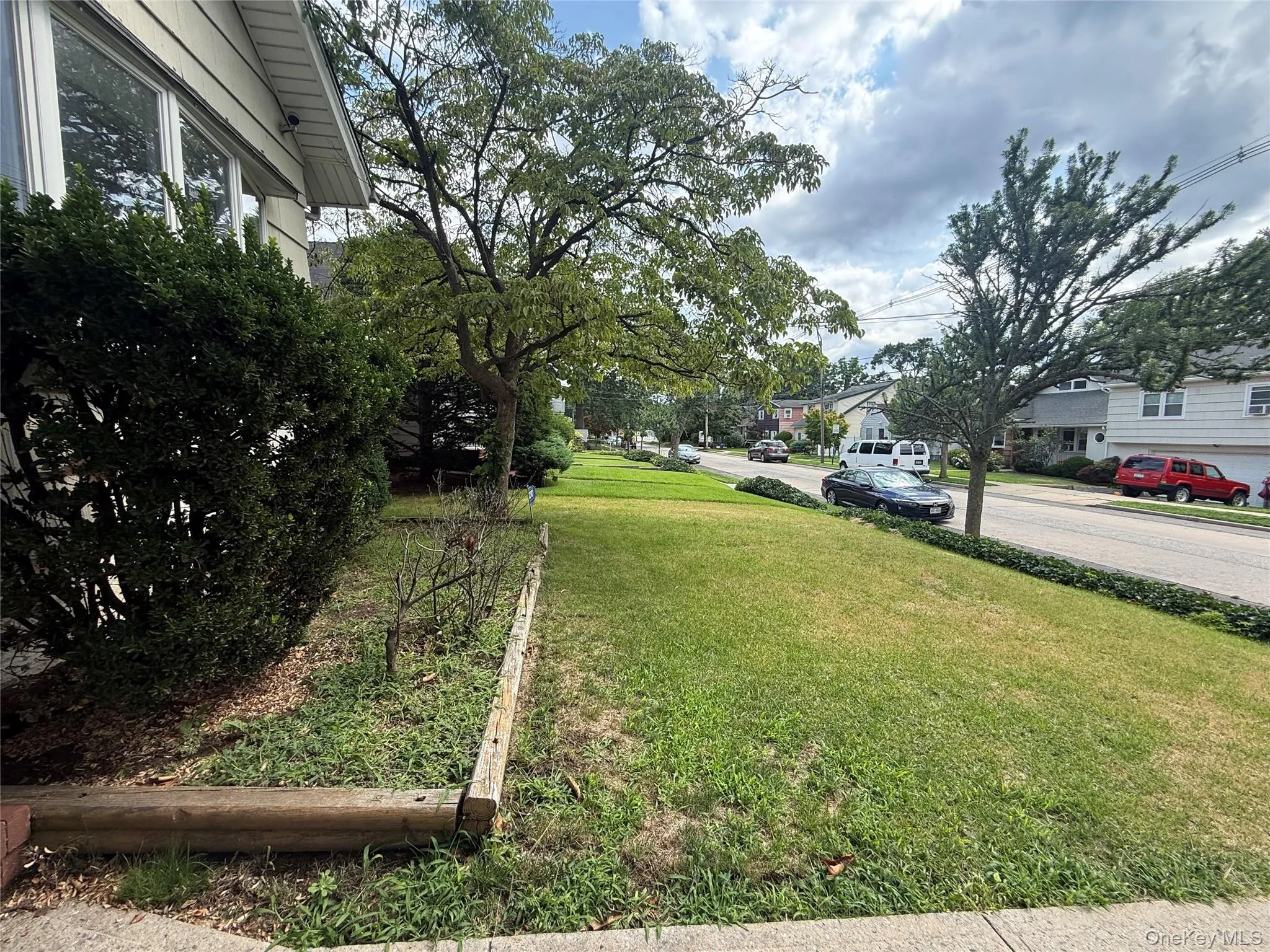 Expansive front yard featuring a manicured lawn, established shrubbery, and mature trees Expansive front yard featuring a manicured lawn, established shrubbery, and mature trees